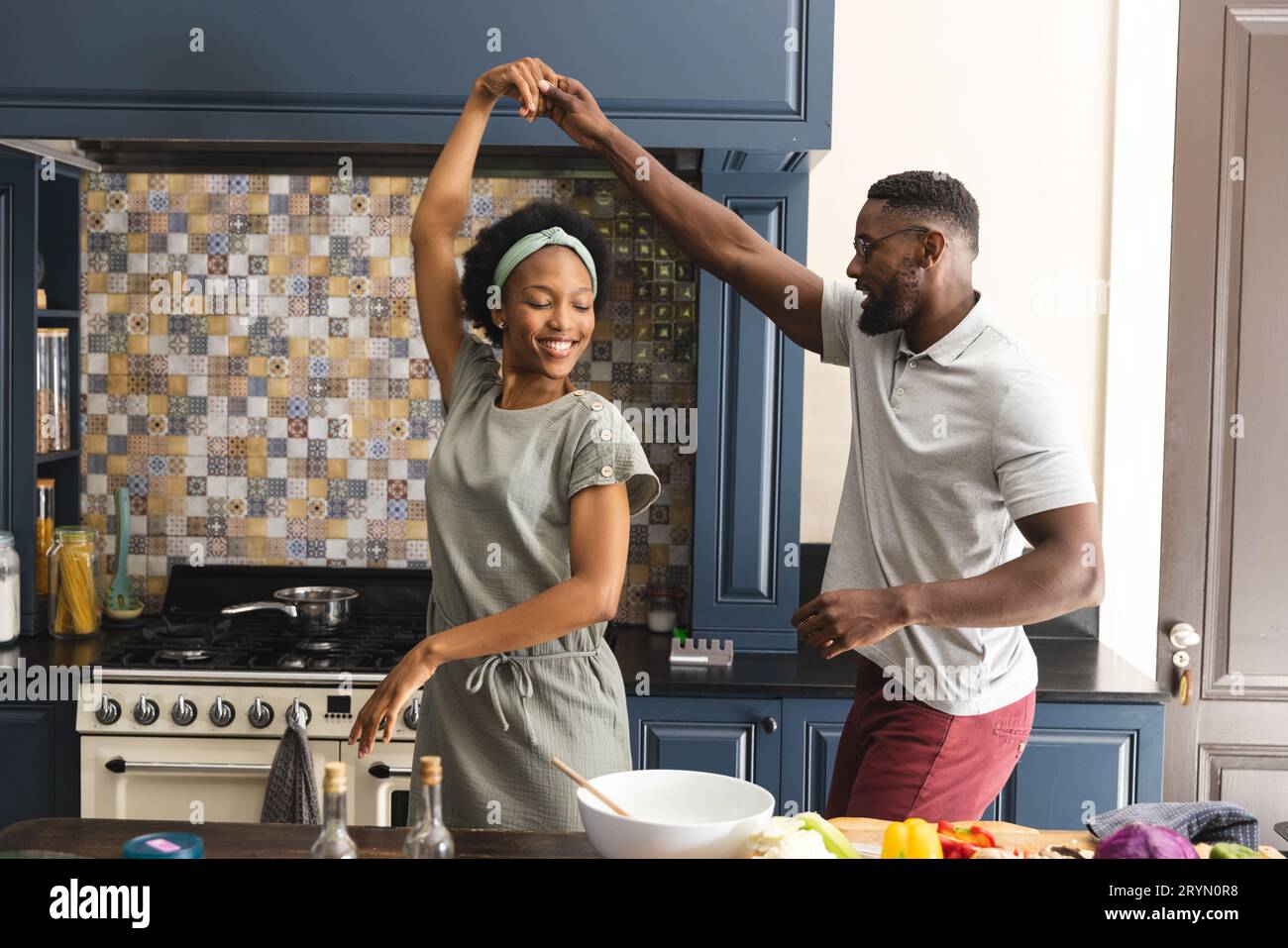 Happy african american couple dancing while preparing meal together in ...