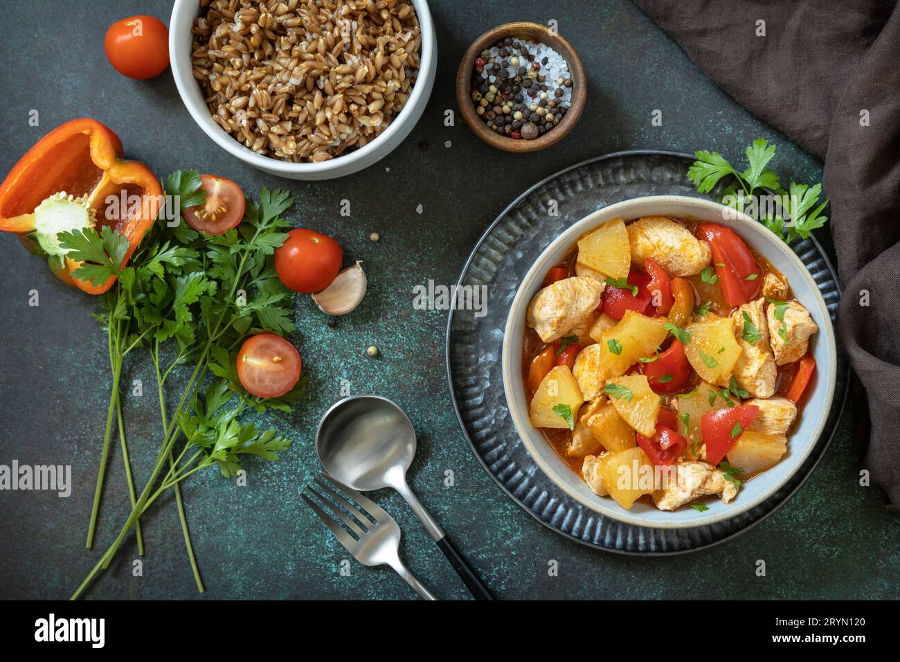 The concept of Diet menu. Homemade turkey or chicken with pineapple sauce and boiled spelled on a dark stone table. Top view fla Stock Photo