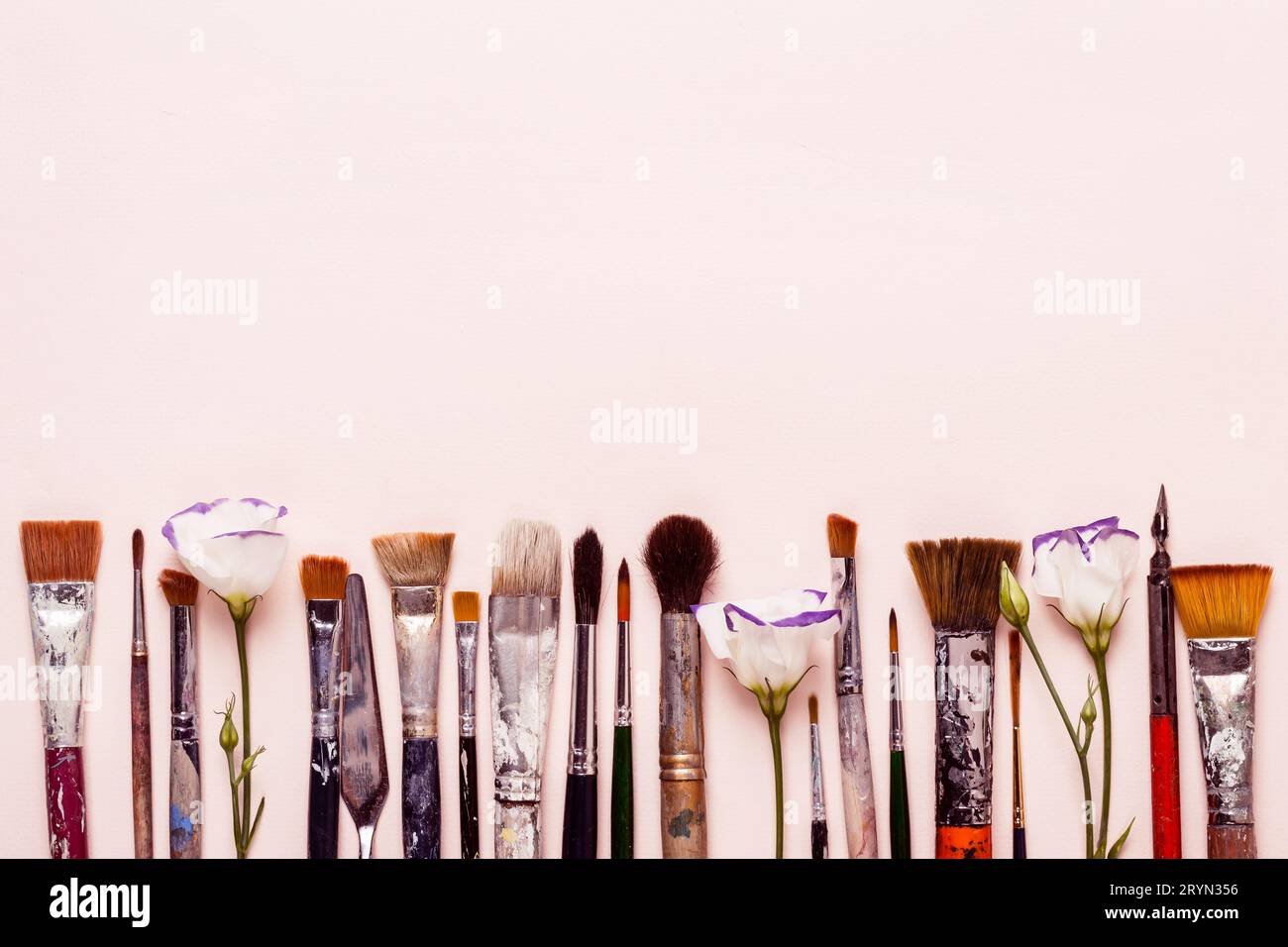 Art Creativity pink background. Row of different brushes and flowers Stock Photo