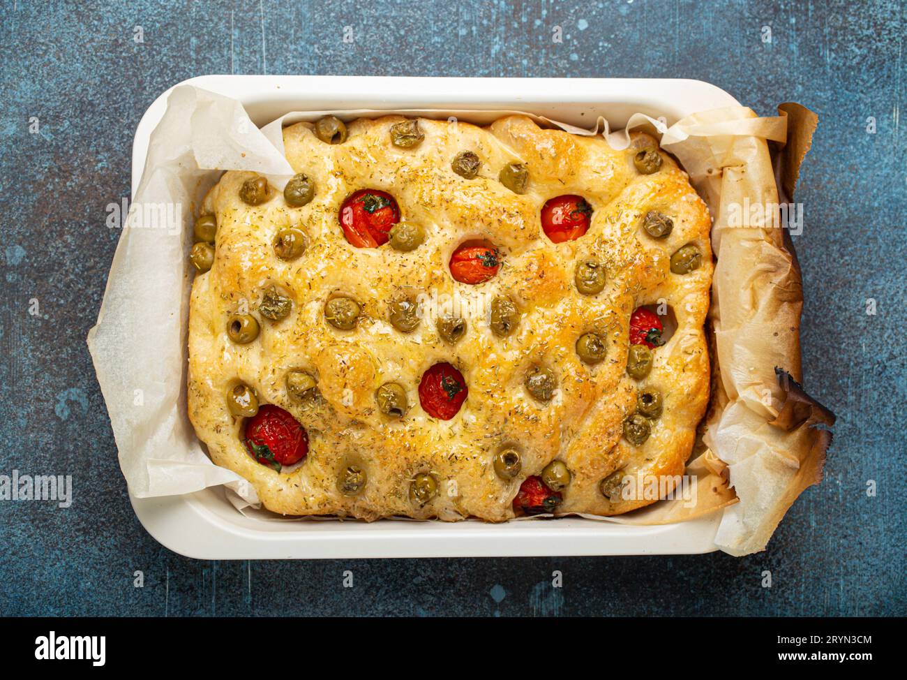 Overhead of Traditional Italian Homemade Flat Bread Focaccia with Green Olives, Olive Oil, Cherry Tomatoes and Rosemary in Bakin Stock Photo