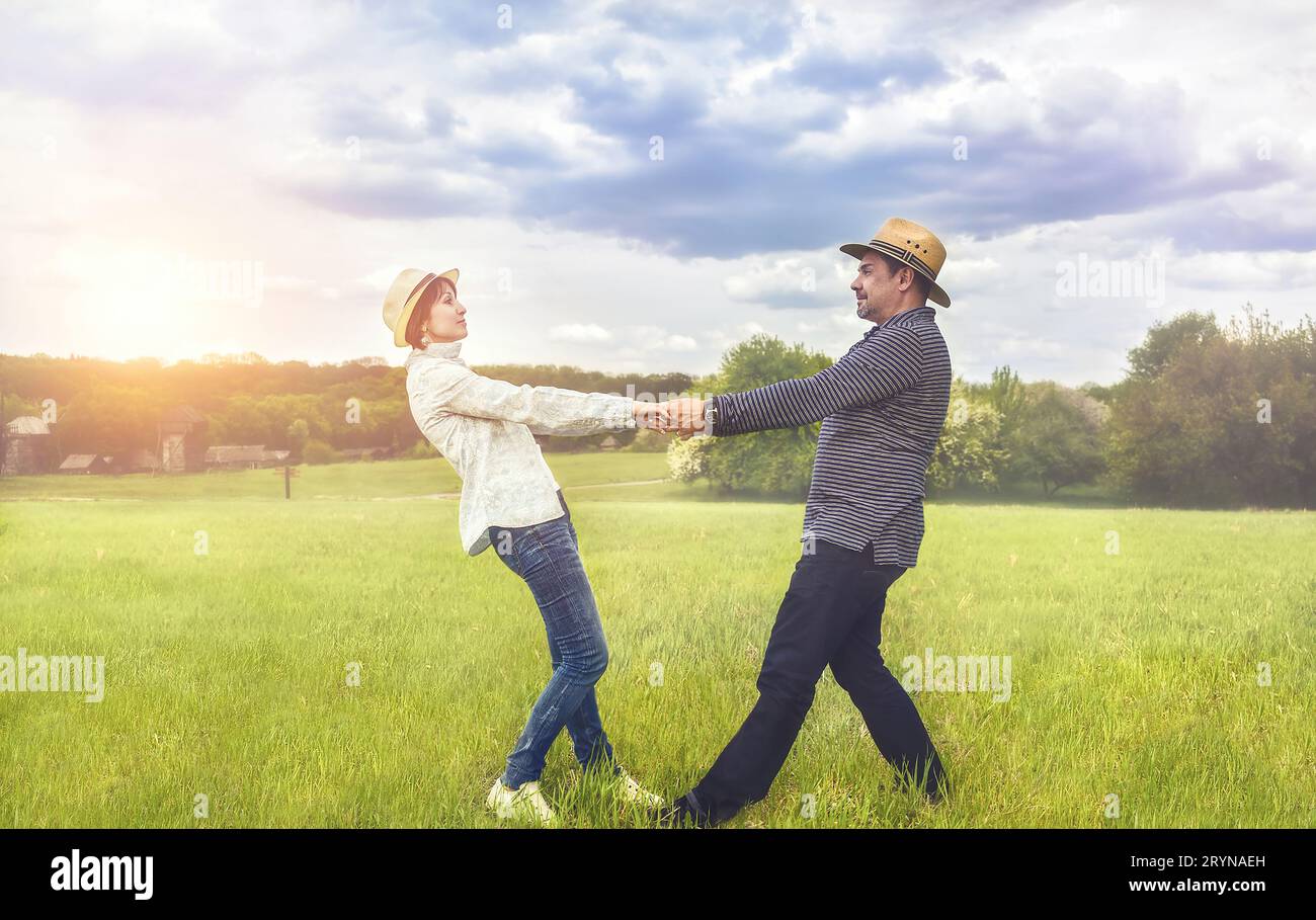 A portrait of a happy middle-aged couple holding hands in the field. Stock Photo