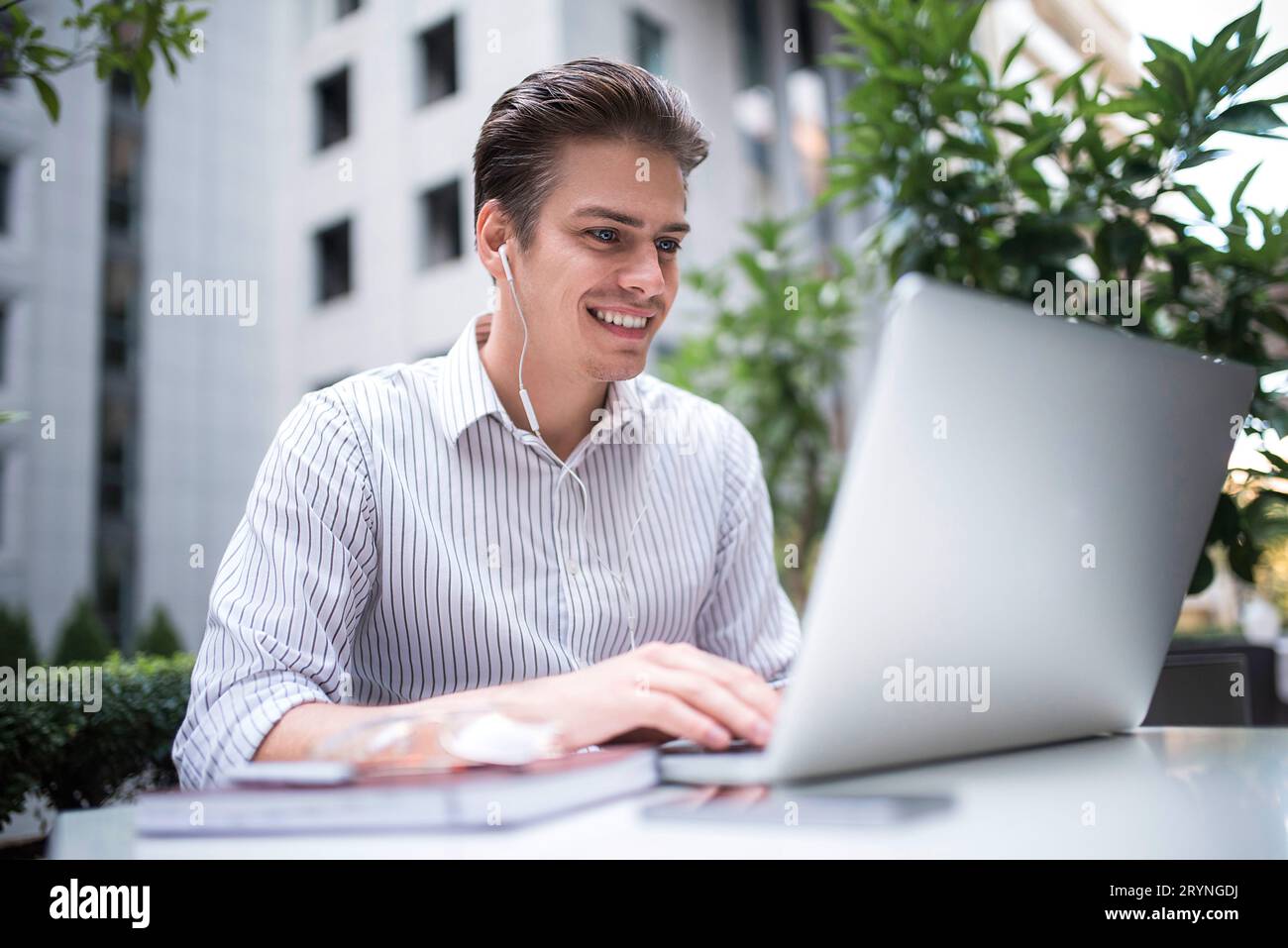 Smart attitude. Positive handsome man using a laptop and sitting in the cafe while surfing the internet have a web conference. W Stock Photo