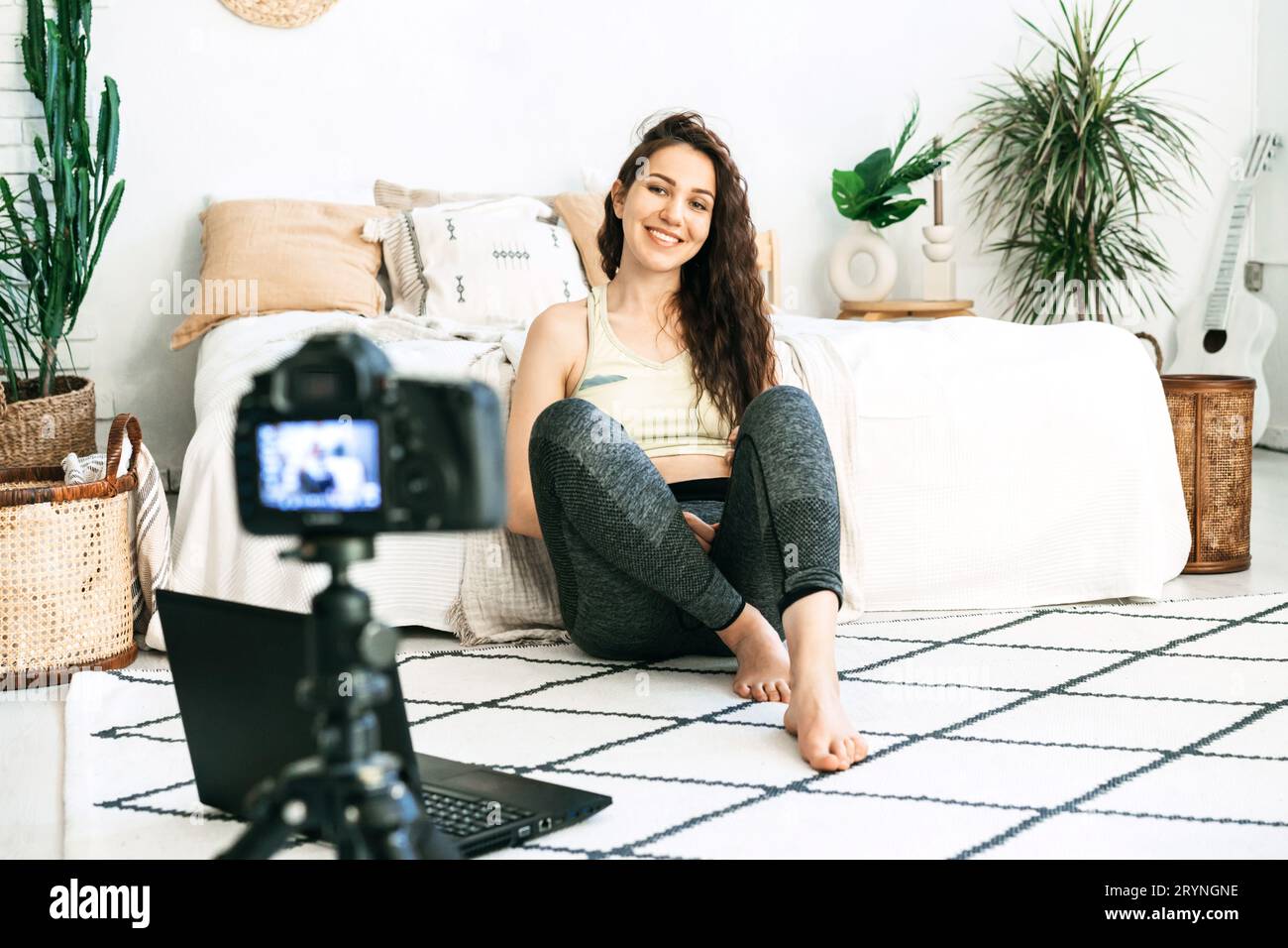Curly-haired girl in sportswear in front of the camera on the floor. Video blogging Stock Photo