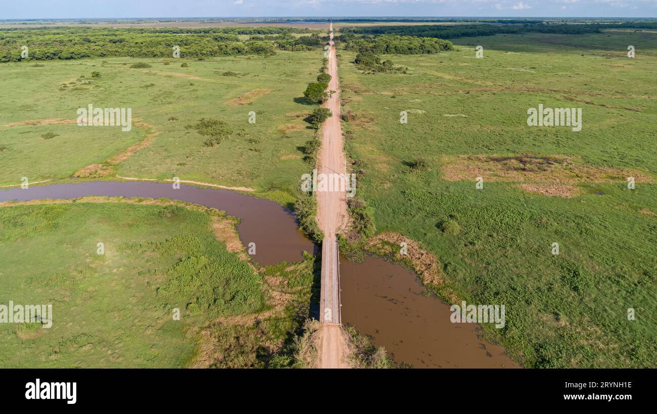 Aerial view of Transpantaneira dirt road crossing a river by a wooden bridge, North Pantanal Wetland Stock Photo
