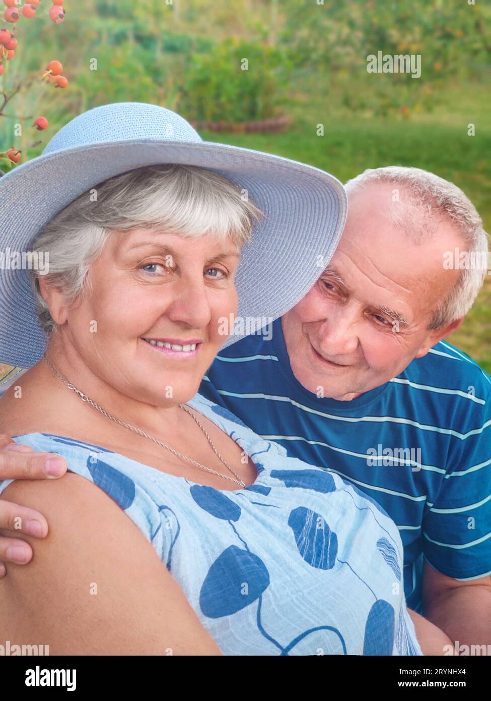 Authentic outdoor shot of aging couple having fun in the garden and blessed with love. During their game man is trying to kiss h Stock Photo