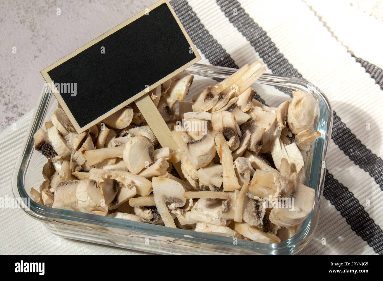 Frozen food sliced mushrooms champignon with blackboard wooden label copy space for text homemade. Harvesting concept. Stocking Stock Photo