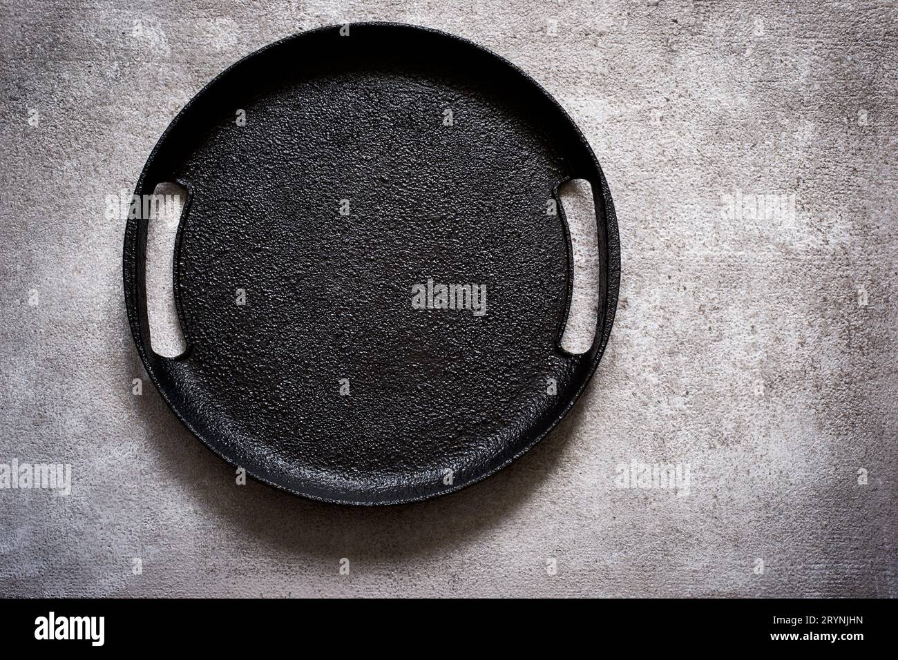Empty rustic black cast iron plate On a concrete background. Top Stock Photo