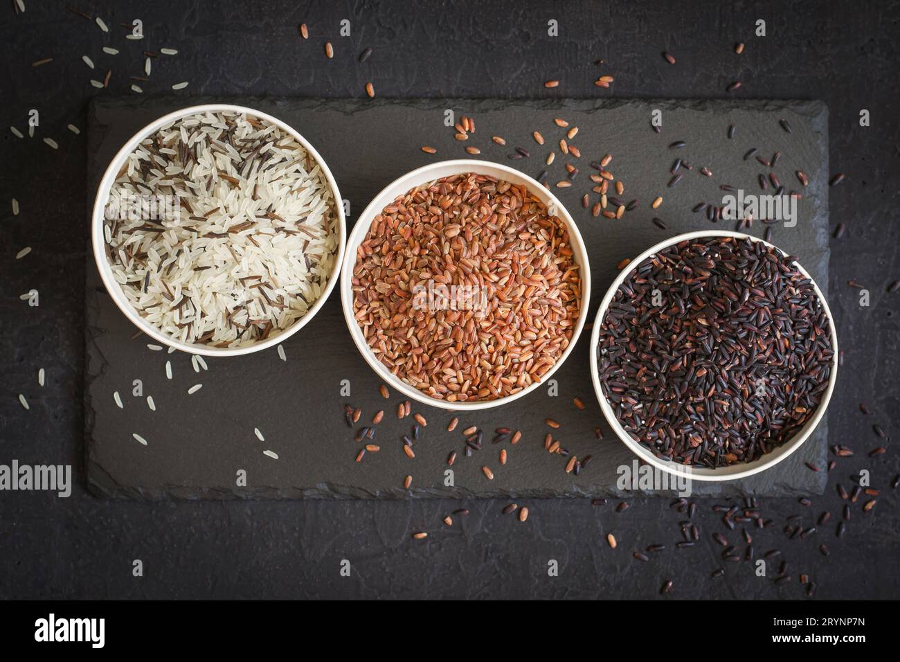 Assorted of variety of gourmet rice in bowls On black background. Top view Stock Photo