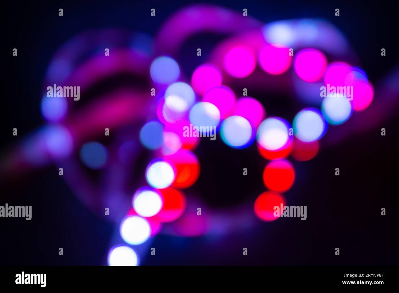 Purple Neon bokeh lights on black. Abstract blurred background Stock Photo
