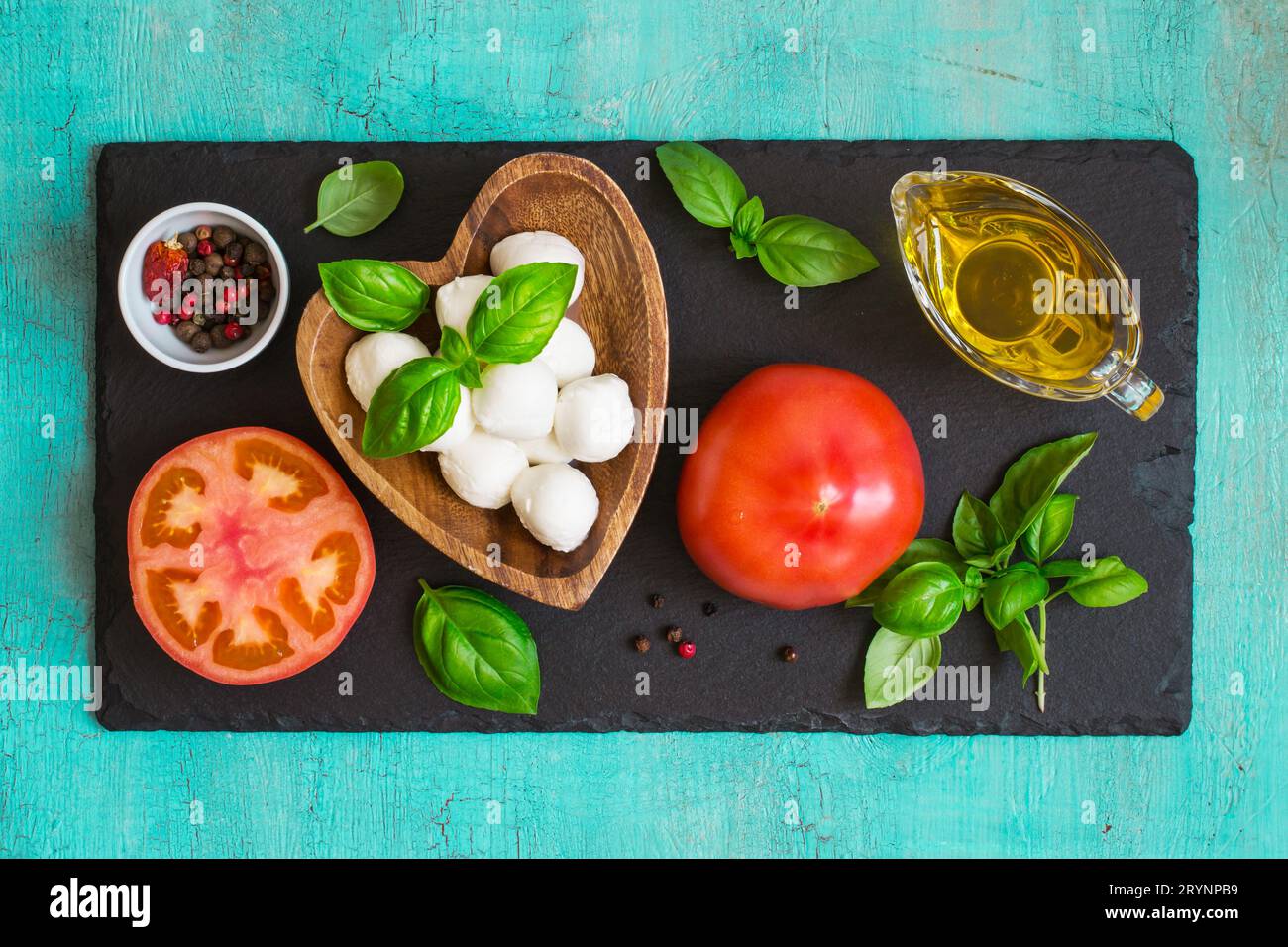 Mozzarella cheese, tomatoes and basil on a turquoise table. Conc Stock Photo