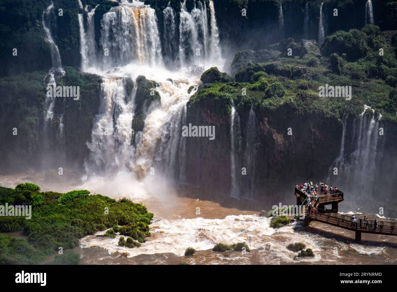 Close-up view to spectacular waterfalls with lush green vegetation and a visitor platform, Iguazu Fa Stock Photo