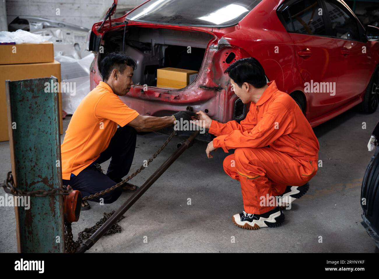 Mechanic testing strength and reliability of chain hoist for car towing