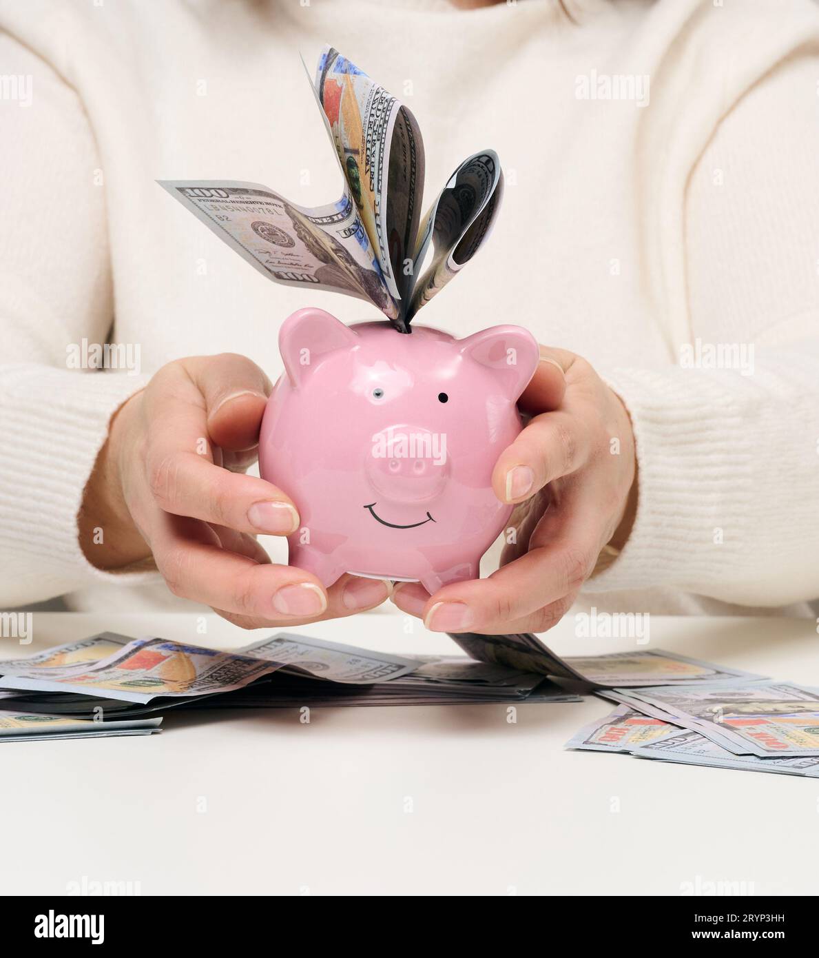 Woman holding pink ceramic piggy bank and paper american dollars. Wealth concept, bargain, accumulation. High profitable margin Stock Photo