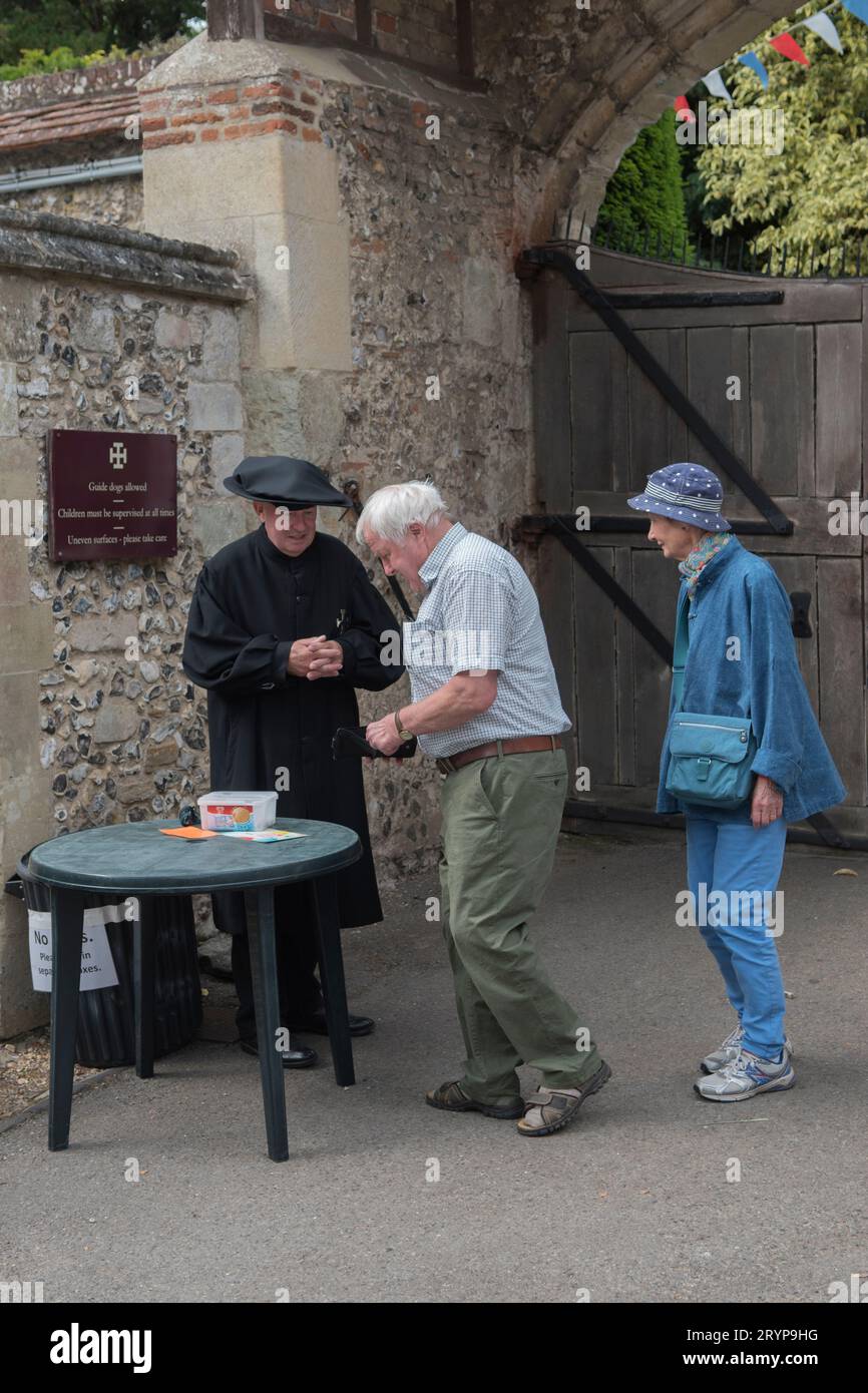 Hospital of St Cross and Almshouse of Noble Poverty annual summer fete thats has taken place for over 150 years. About 2,000 people attended in 2022. One of the Brothers collects the entry fee at the front gate to the Hospital complex.  Winchester, Hampshire, England 25th June 2022.  2020s UK HOMER SYKES Stock Photo