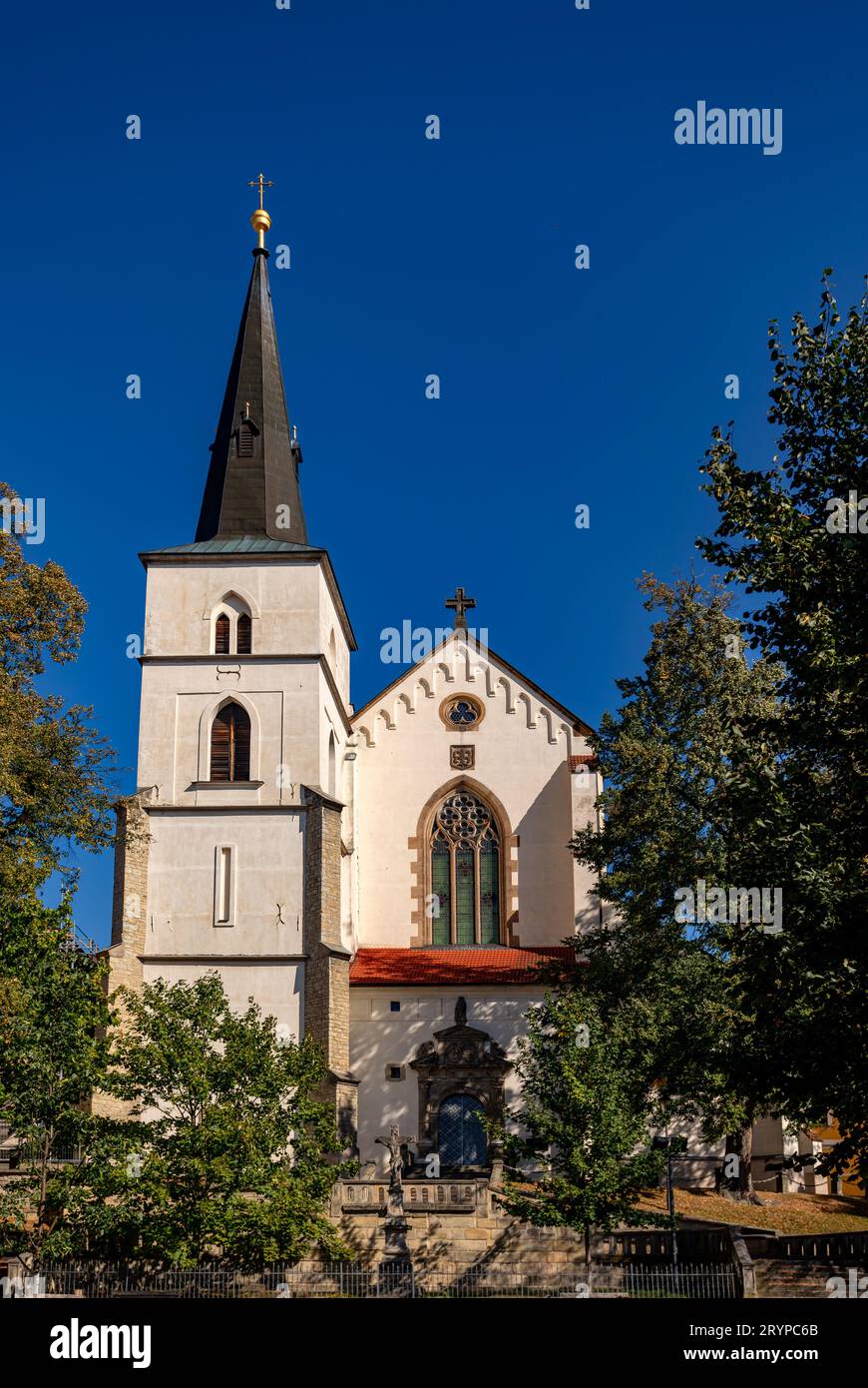 Gothic medieval church of the Exaltation of the Holy Cross with tower at sunny summer day, Fountain in Monastery Garden, Sculpture Chic. Litomysl, Cze Stock Photo