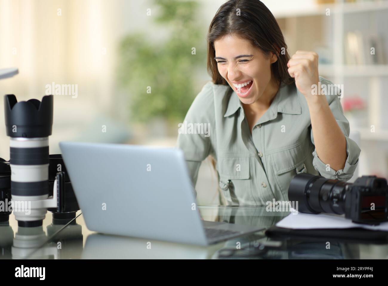 Excited photographer celebrating good result watching laptop content at home Stock Photo