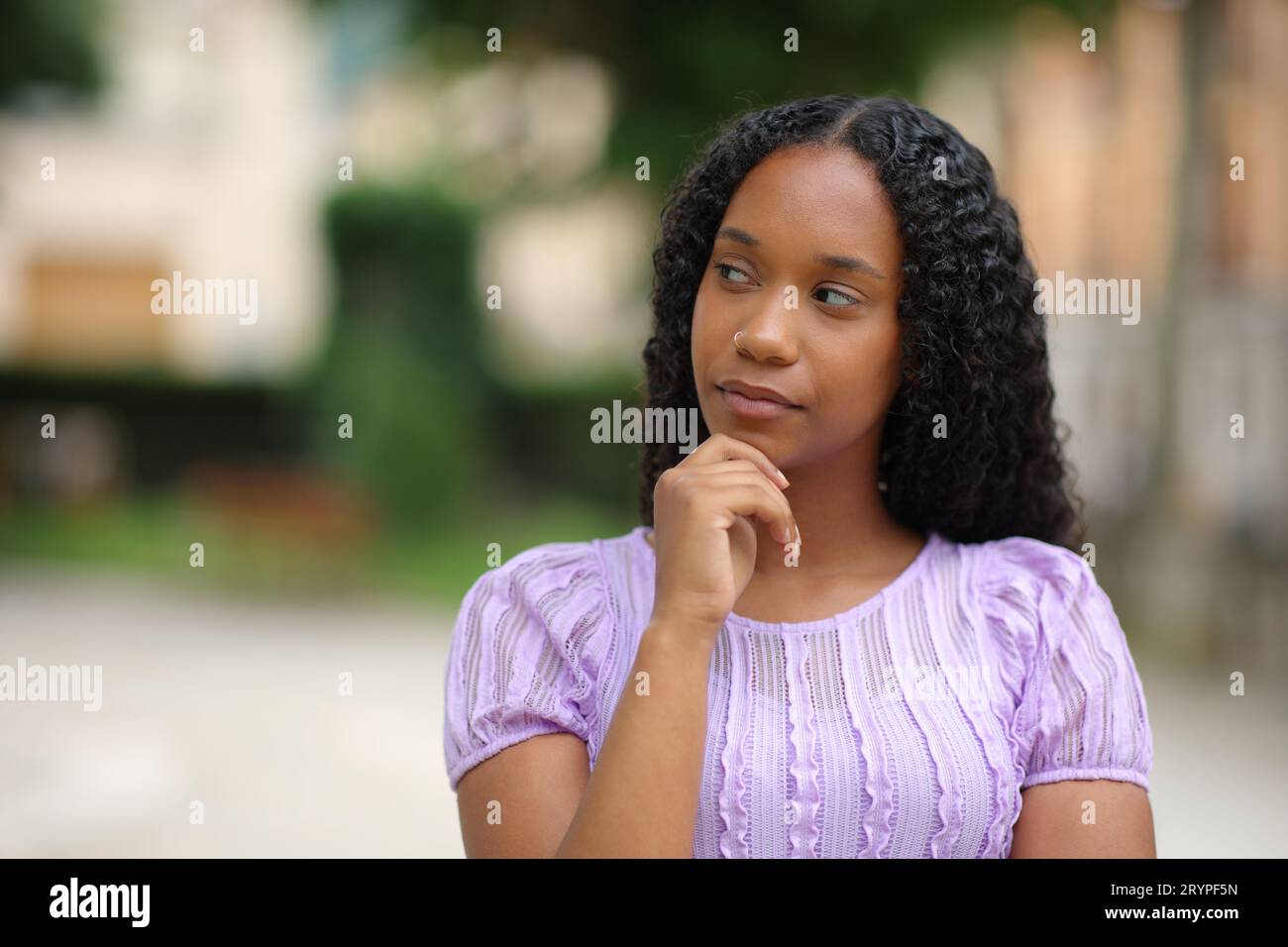 Pensive black woman wondering looking at side in the street Stock Photo