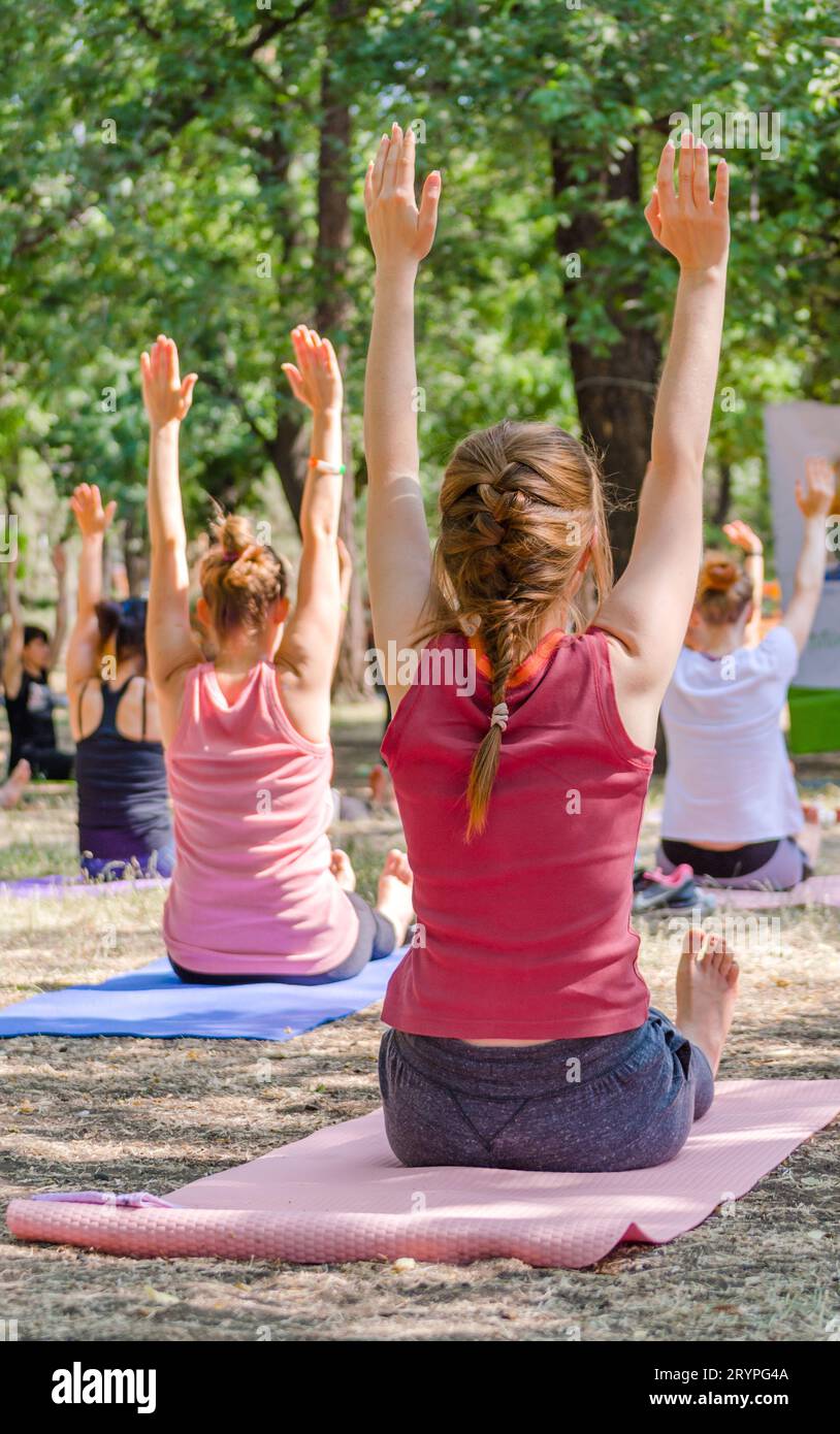 Yoga in a park a group of people sitting on yogamates holding th Stock Photo