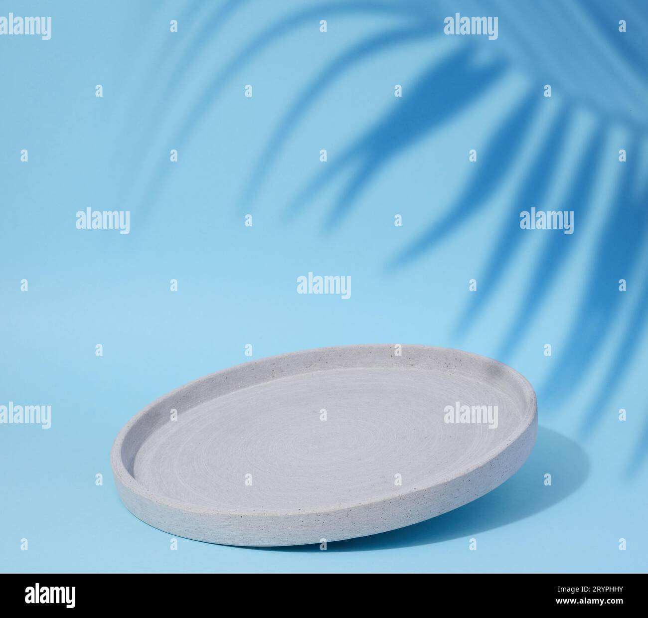Round empty plate on a blue background shadow from a palm leaf Stock Photo