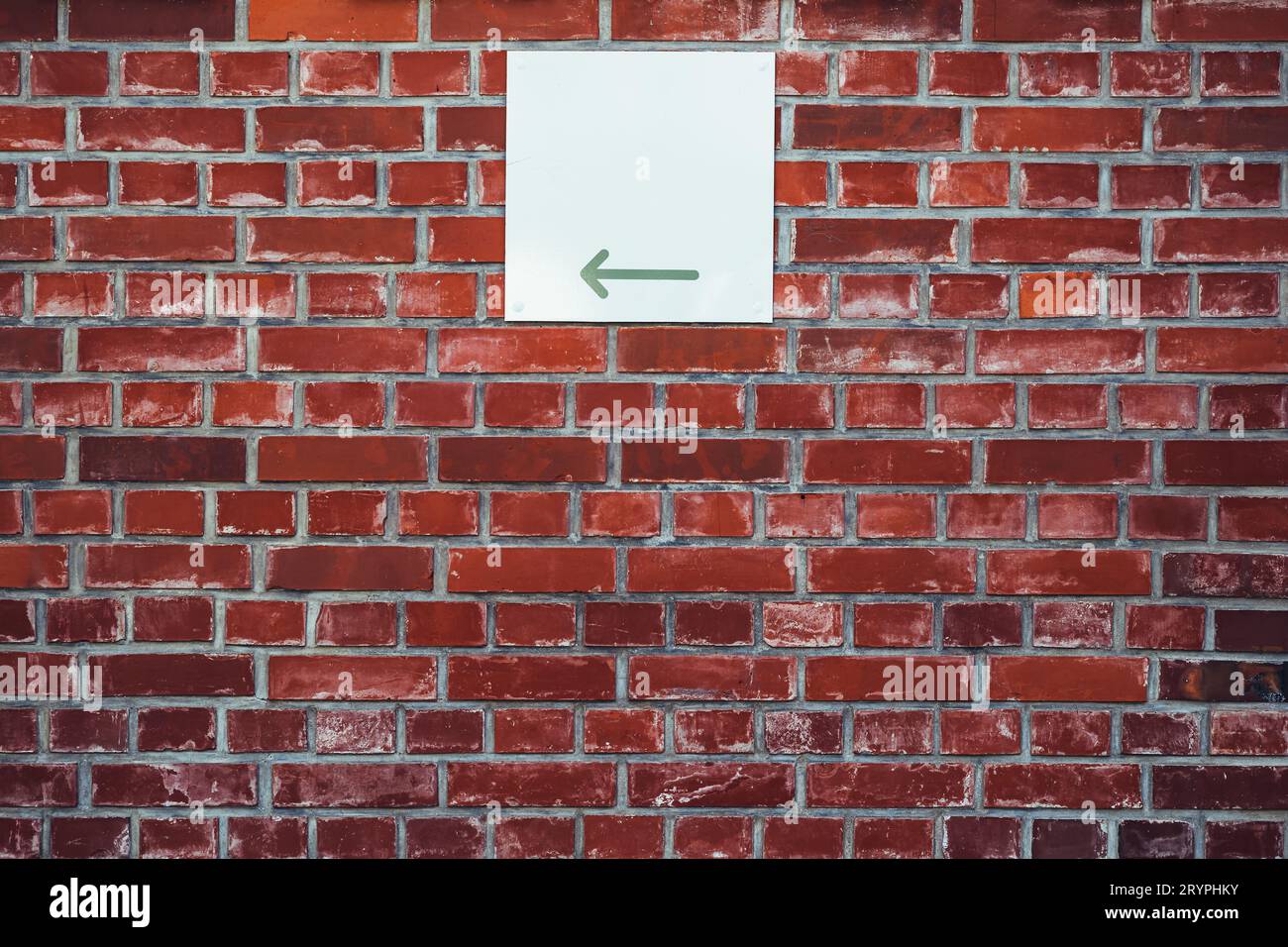 Direction arrow sign board on brick wall facade with copy space Stock Photo