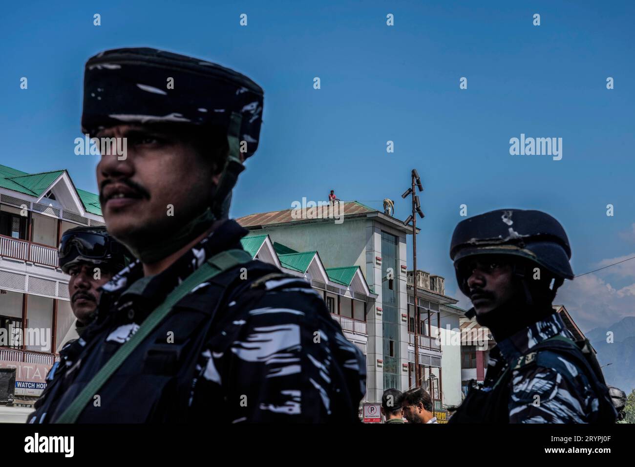 Indian paramilitary soldiers stand guard at a market as painters paint ...