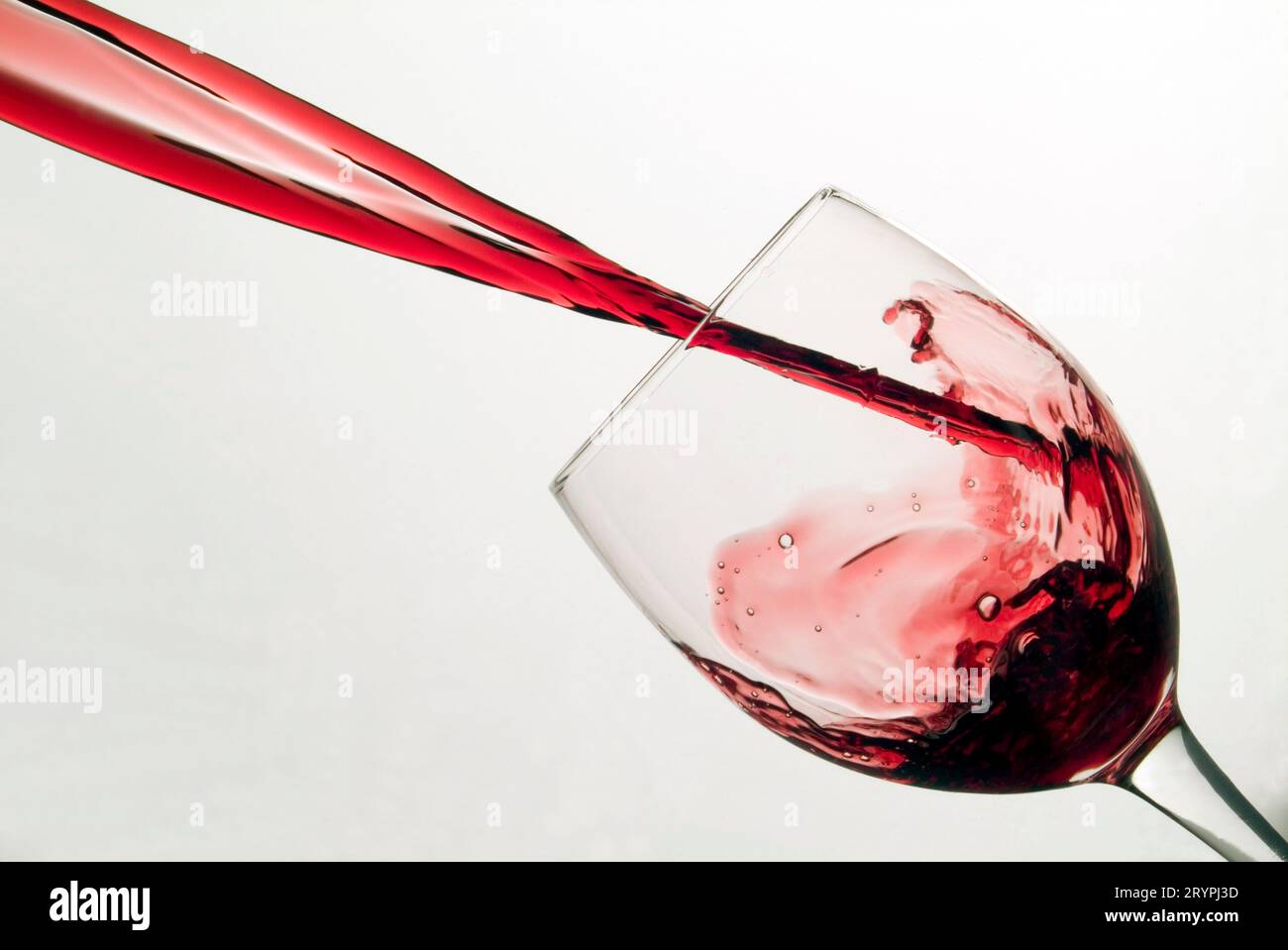 Red wine splashing into a tilted wine glass Stock Photo Alamy