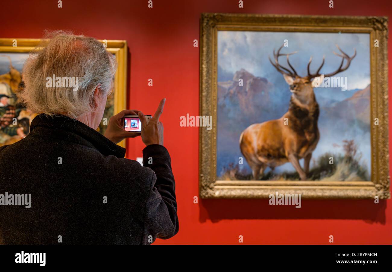 Man taking photo of Monarch of the Glen stag painting by Sir Edwin Landseer, National Galleries of Scotland newly opened extension, Edinburgh, UK Stock Photo
