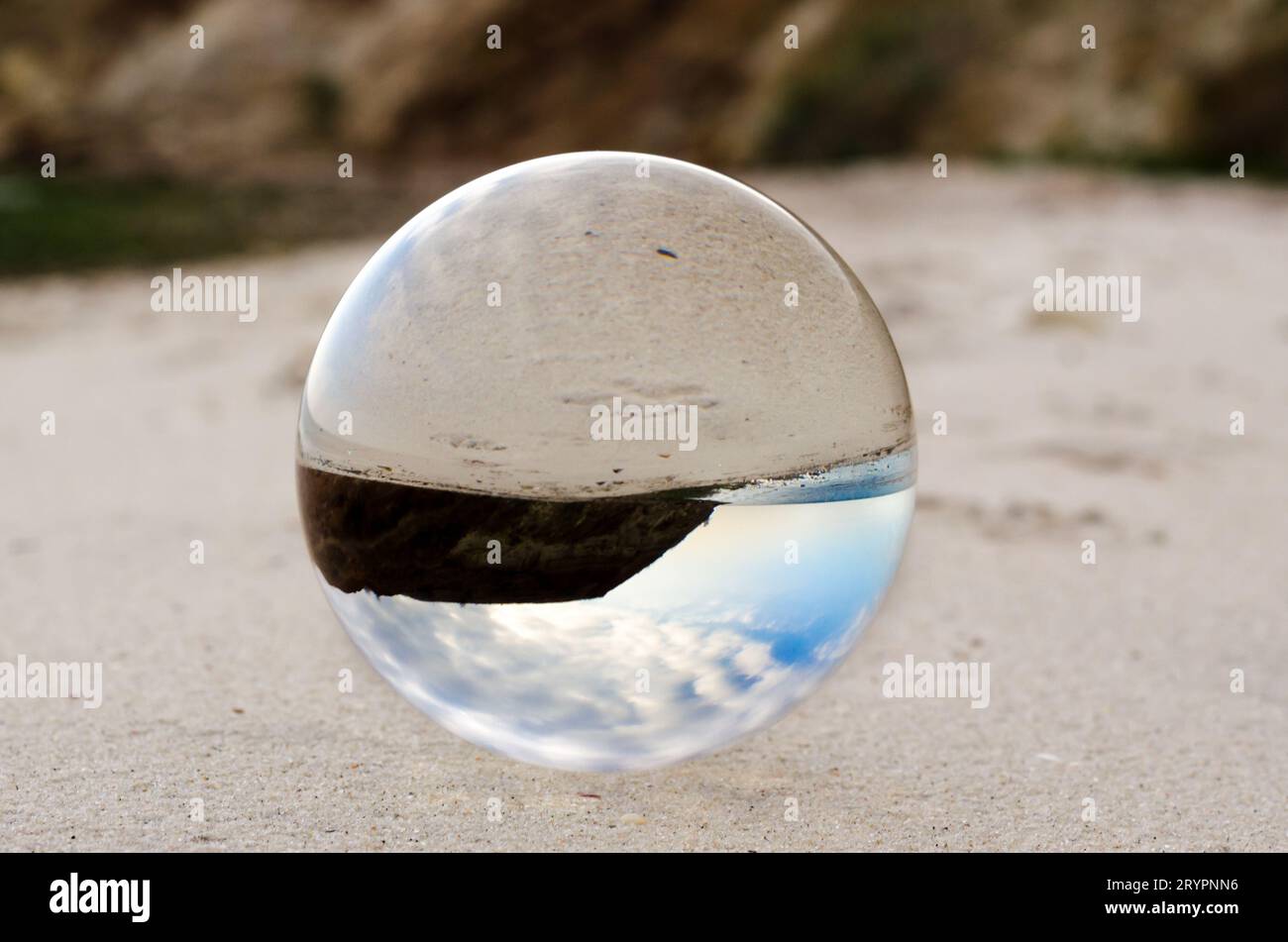 Glass ball lens lies on the sand of the sea shore Stock Photo - Alamy