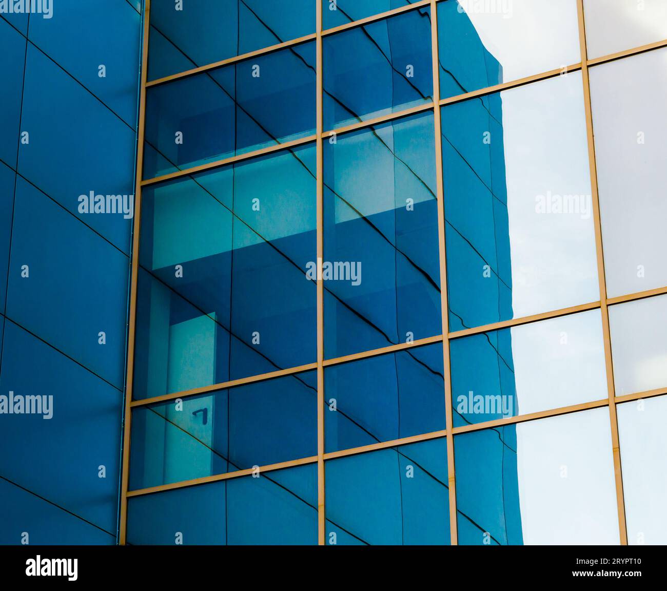 Mirrored windows of the facade of an office building with blue panels and yellow window frames with a distorted reflection of th Stock Photo