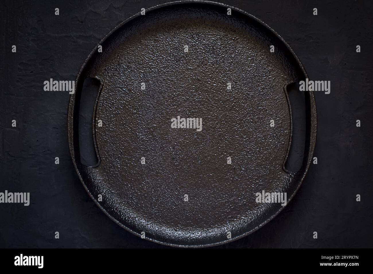 Empty rustic cast iron plate On a black background. Top view wit Stock Photo