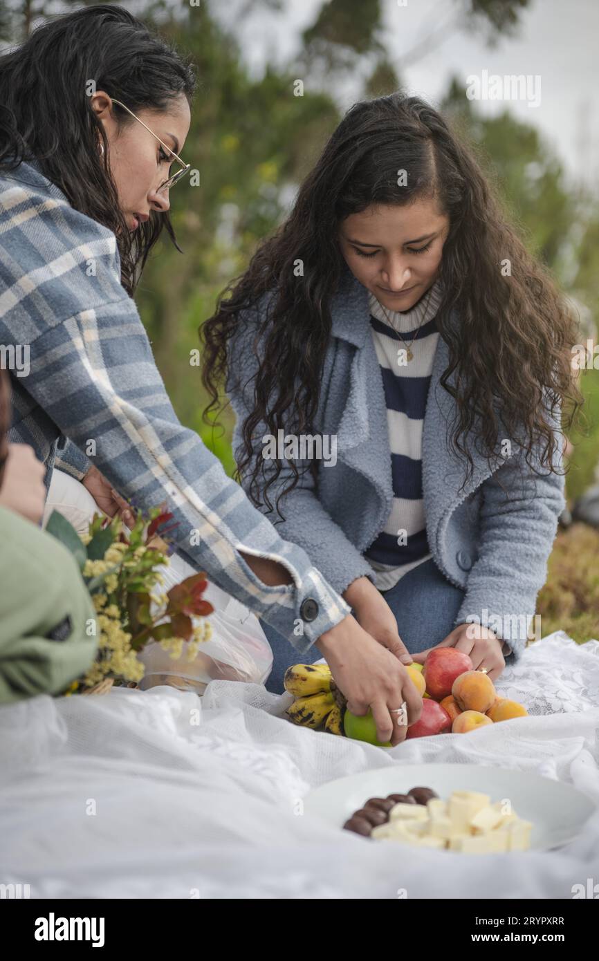 Young Latina women picking fruits on a picnic day in nature Stock Photo