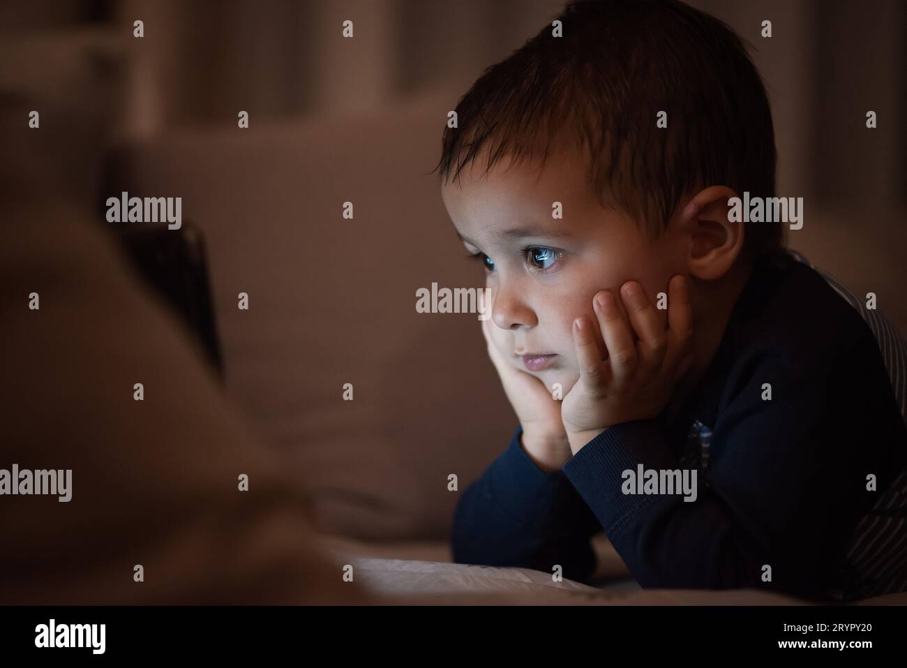 Portrait of a sad little boy sitting on the bed at home Stock Photo