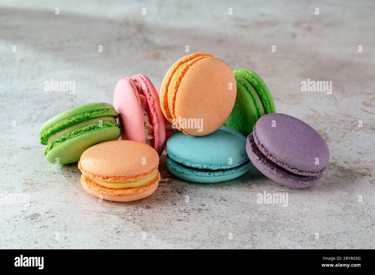 multicolored macaroon cookies lie on a white kitchen table Stock Photo