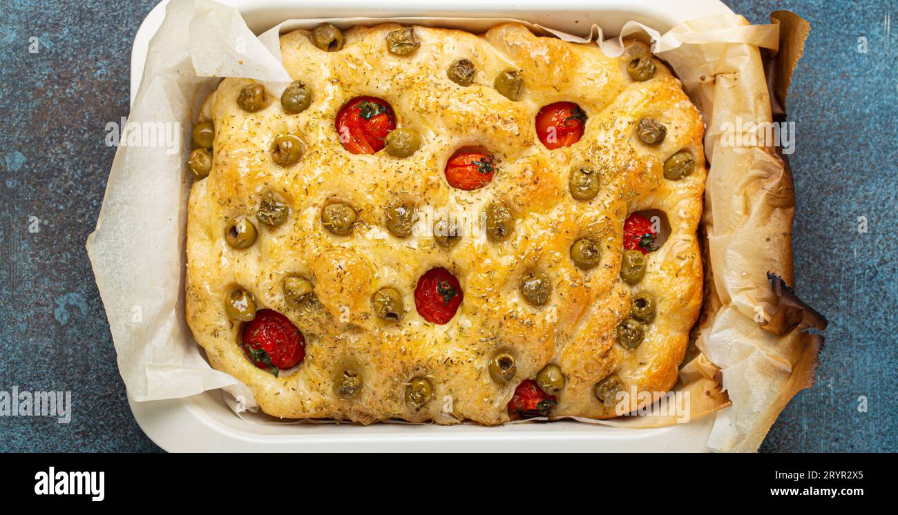 Overhead of Traditional Italian Homemade Flat Bread Focaccia with Green Olives, Olive Oil, Cherry Tomatoes and Rosemary in Bakin Stock Photo