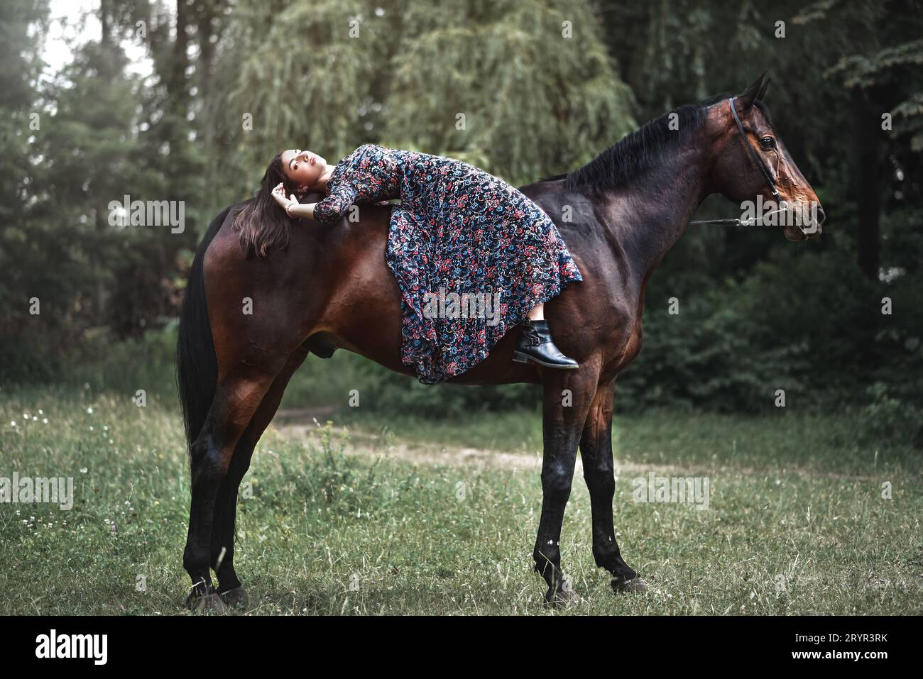 Young pretty latin girl laying on horseback in the forest. love animals concept. love horses Stock Photo