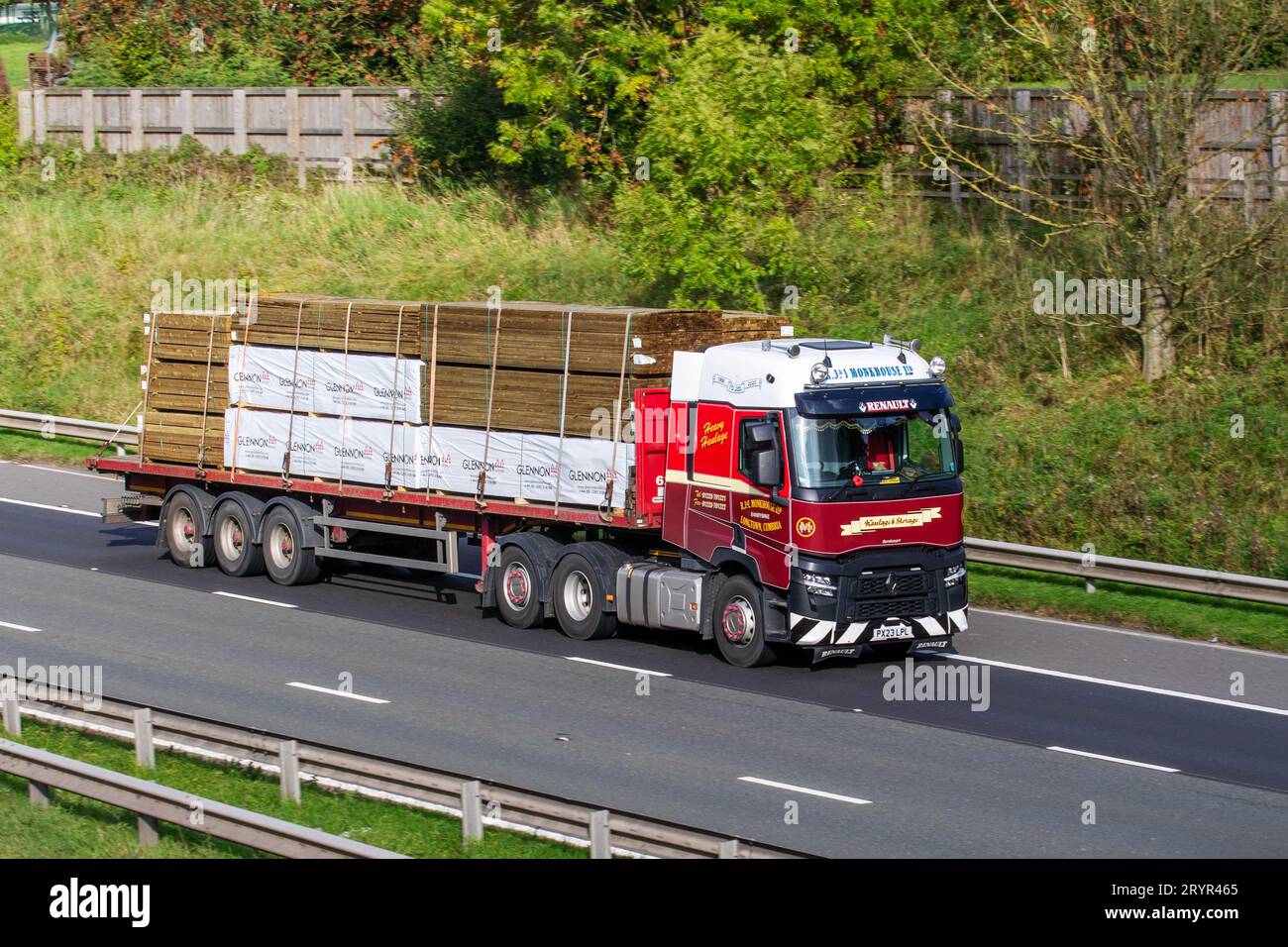 R J & I MONKHOUSE LTD a haulage transport company based in  Carlisle transporting Glennon Timber machined products on flatbed Renault 480.26 6x2 TML red 12777cc truck; travelling at speed on the M6 motorway in Greater Manchester, UK Stock Photo
