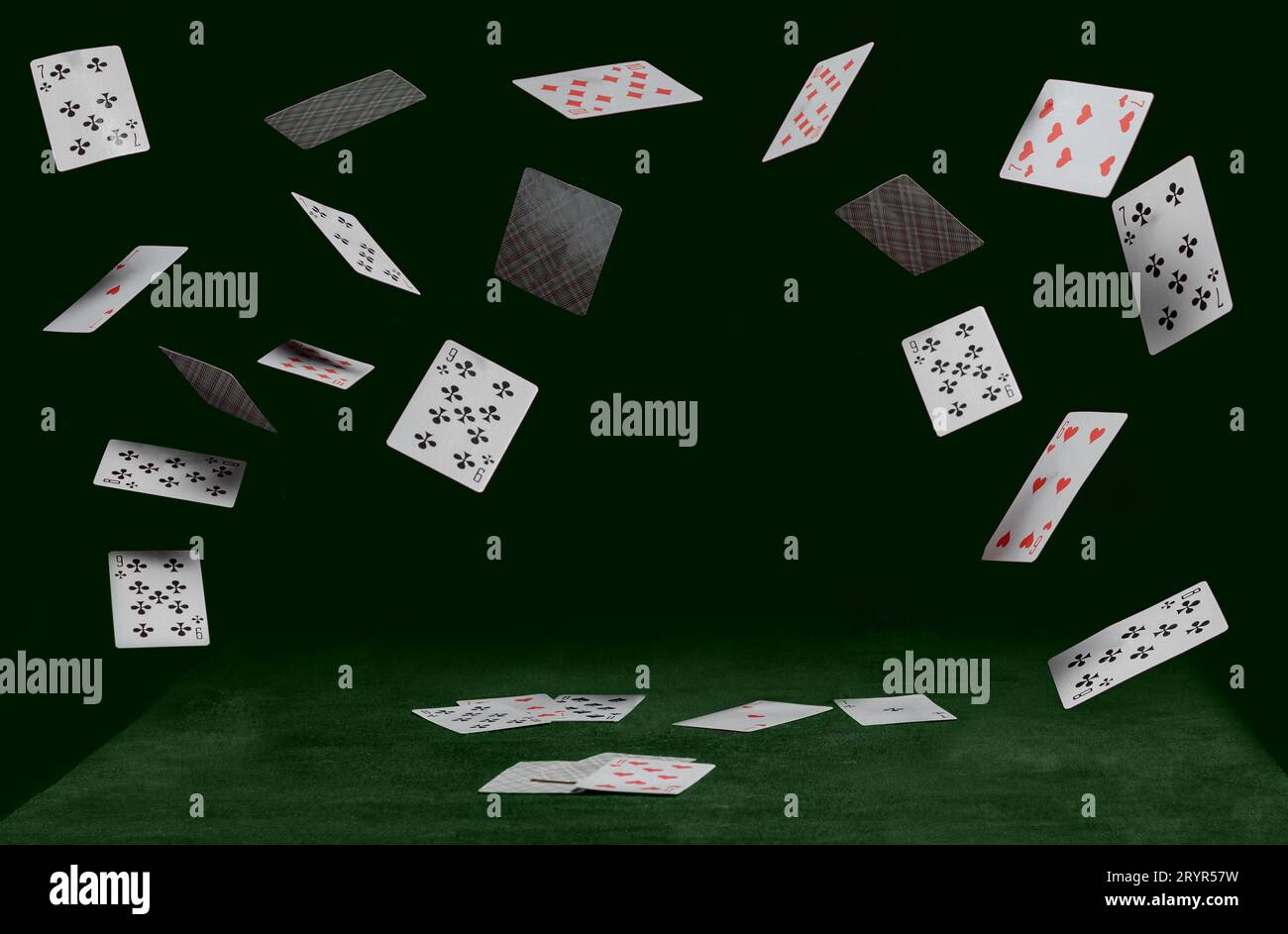 Playing cards fall on a green table Stock Photo