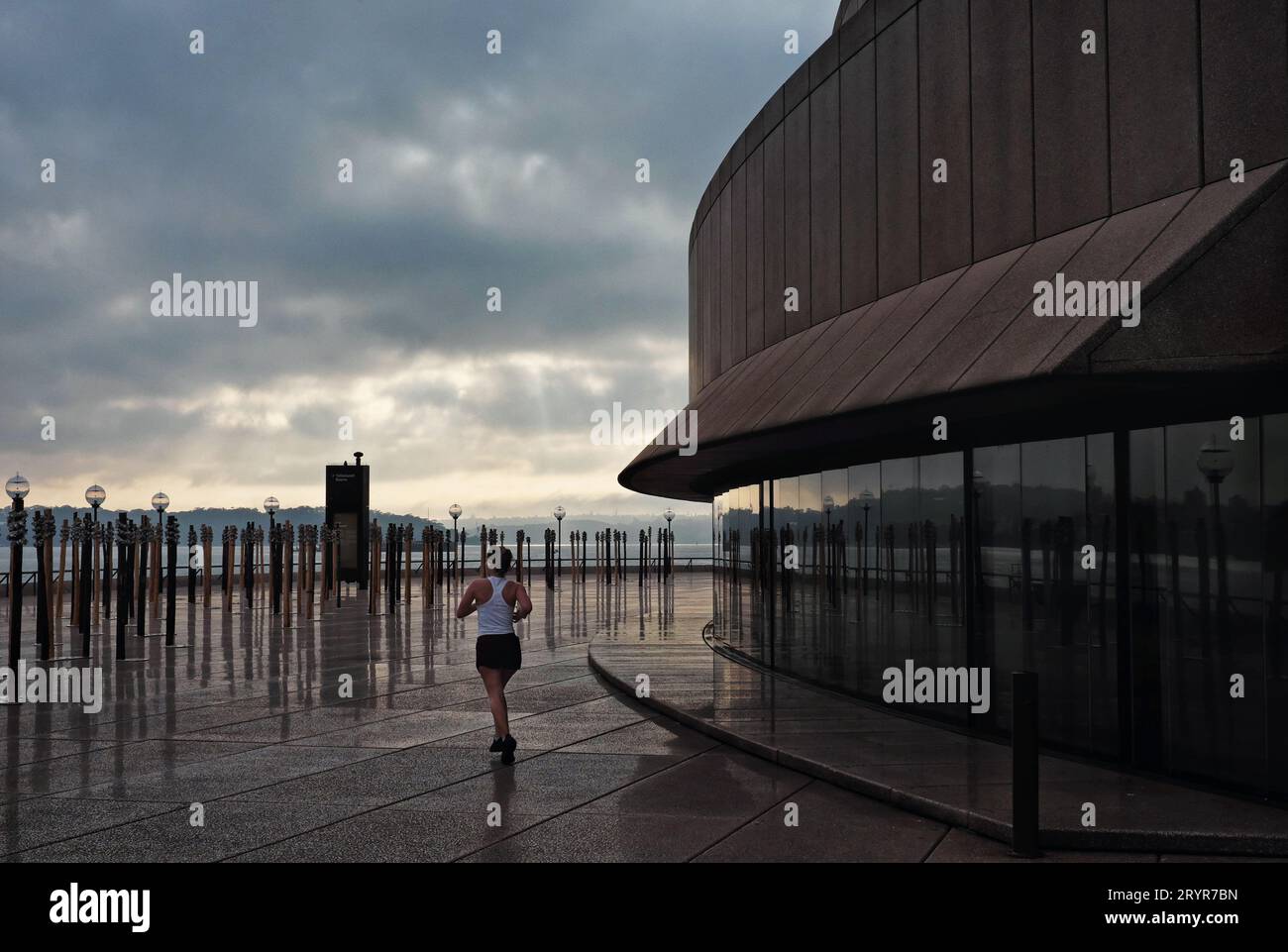 Early morning at the Sydney Opera House a jogger passes the Monumental Public Artwork Whispers by artist Megan Cope on the Northern Broadwalk Stock Photo