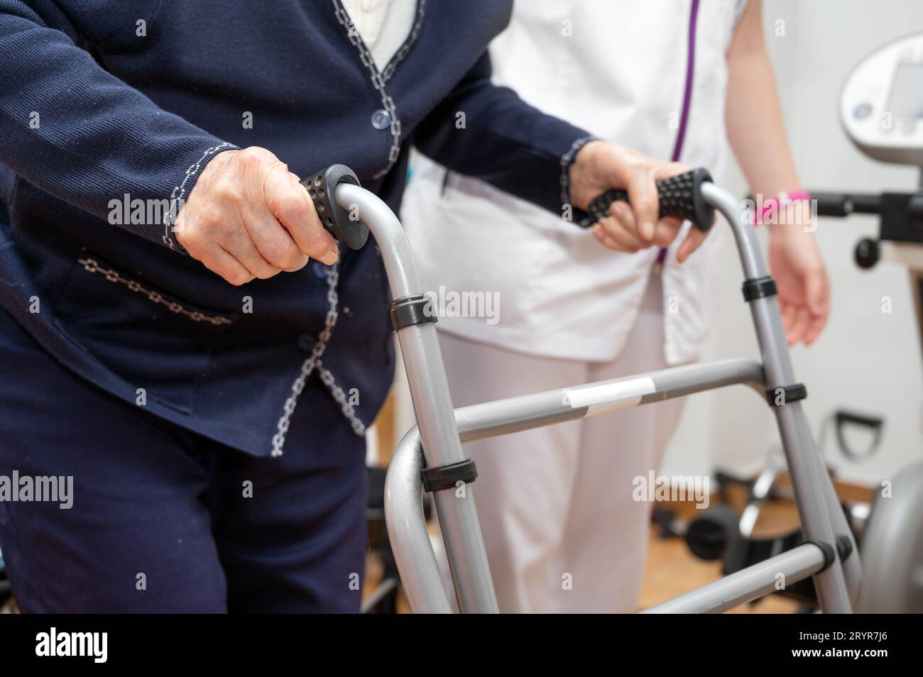 Nurse assists her senior patient on folding walker. Recuperation for elderly, seniors care, nursing home. Stock Photo