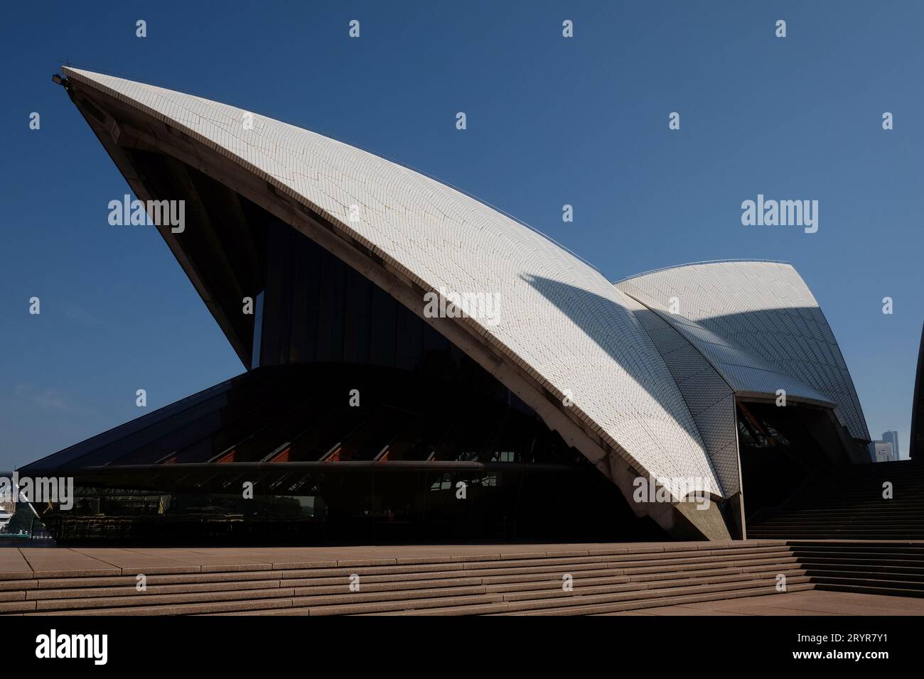 Restaurant pavilion glass walls and the white shells against a blue sky from the upper podium of the Sydney Opera House, New South Wales, Australia Stock Photo