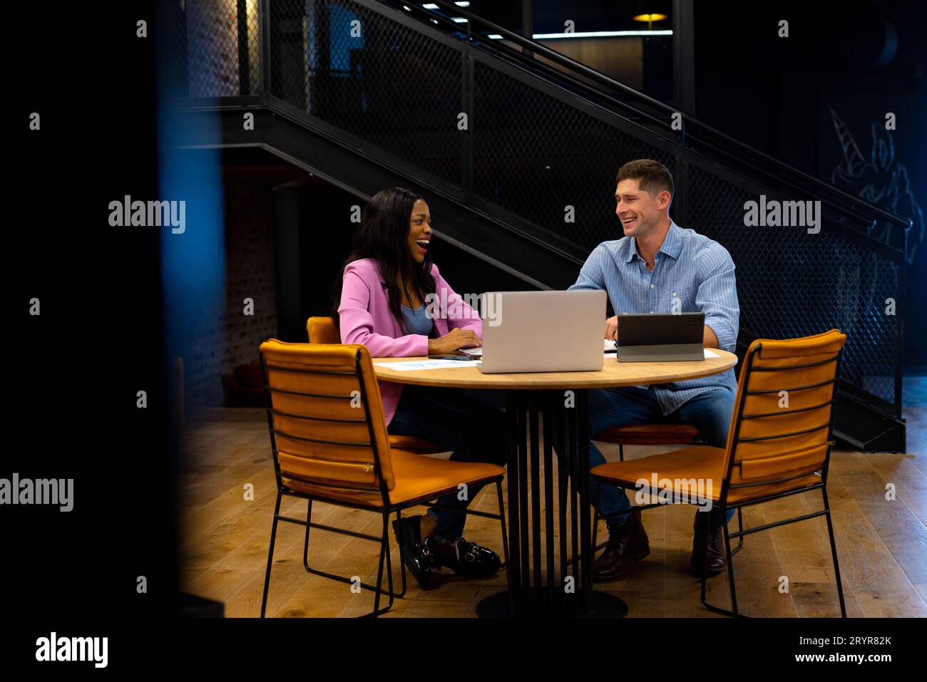 Happy diverse male and female colleague using tablet and laptop in ...