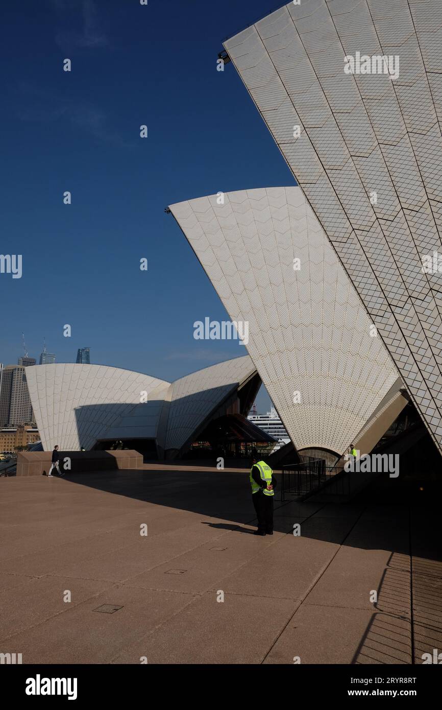 Profile view of Sydney Opera House sails, Opera Theatre, Concert Hall & Bennelong Restaurant - Security guards and barrier fencing on the upper podium Stock Photo