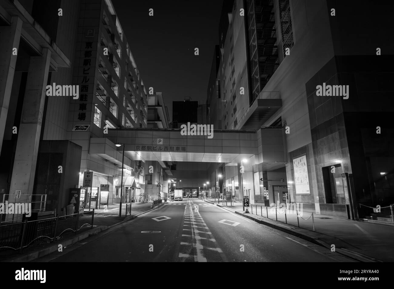 A nighttime view of a city street, featuring illuminated buildings and