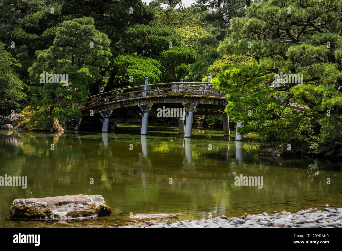 A scenic view of an old bridge that spans across a tranquil lake Stock Photo
