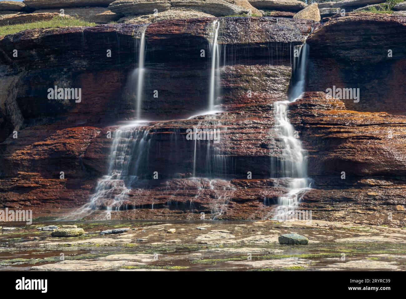 Image showcasing A majestic waterfall cascades down a rocky cliff face into the clear ...