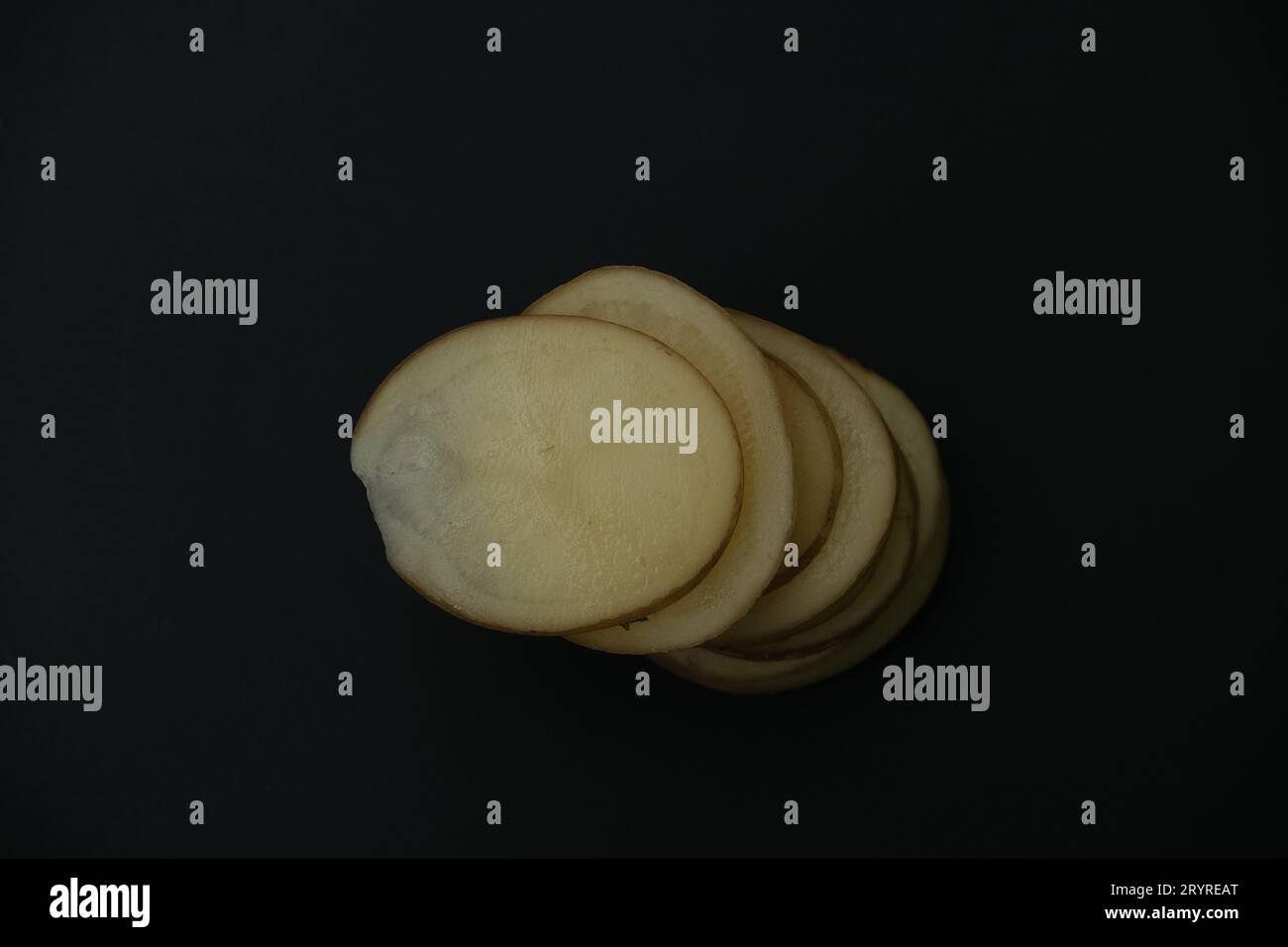 stacked potato slices on black background , top down view Stock Photo