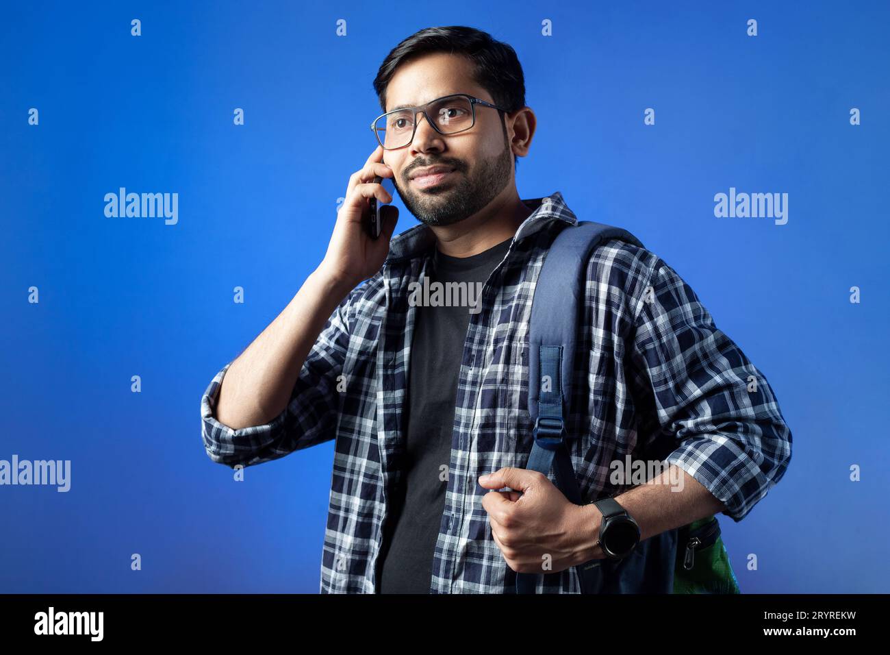 In single color background a happy Indian man talking on smart phone. Stock Photo