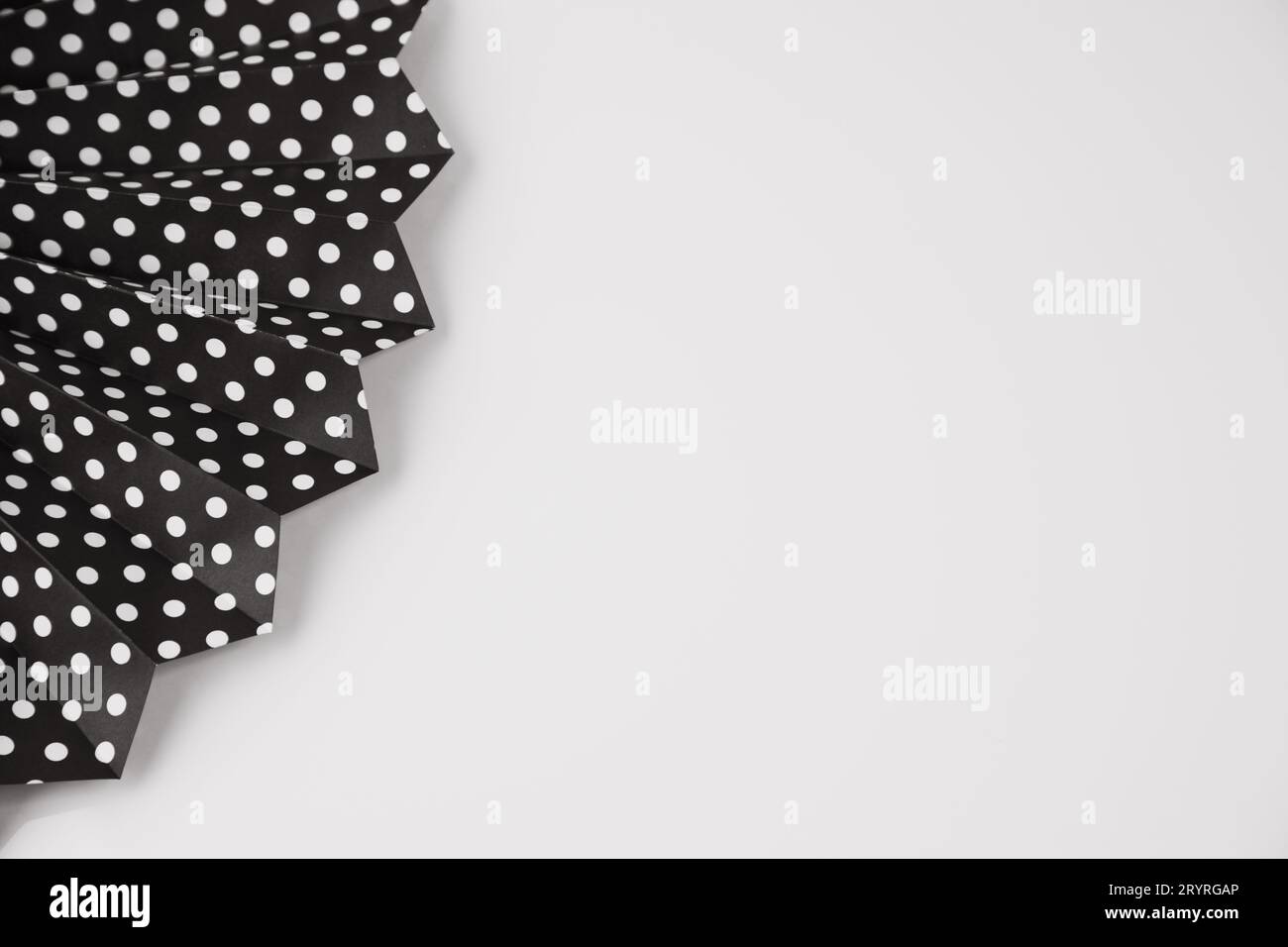 A close-up of a black and white polka dot dress lying on a flat surface such as a table, the fabric of the dress is in focus Stock Photo
