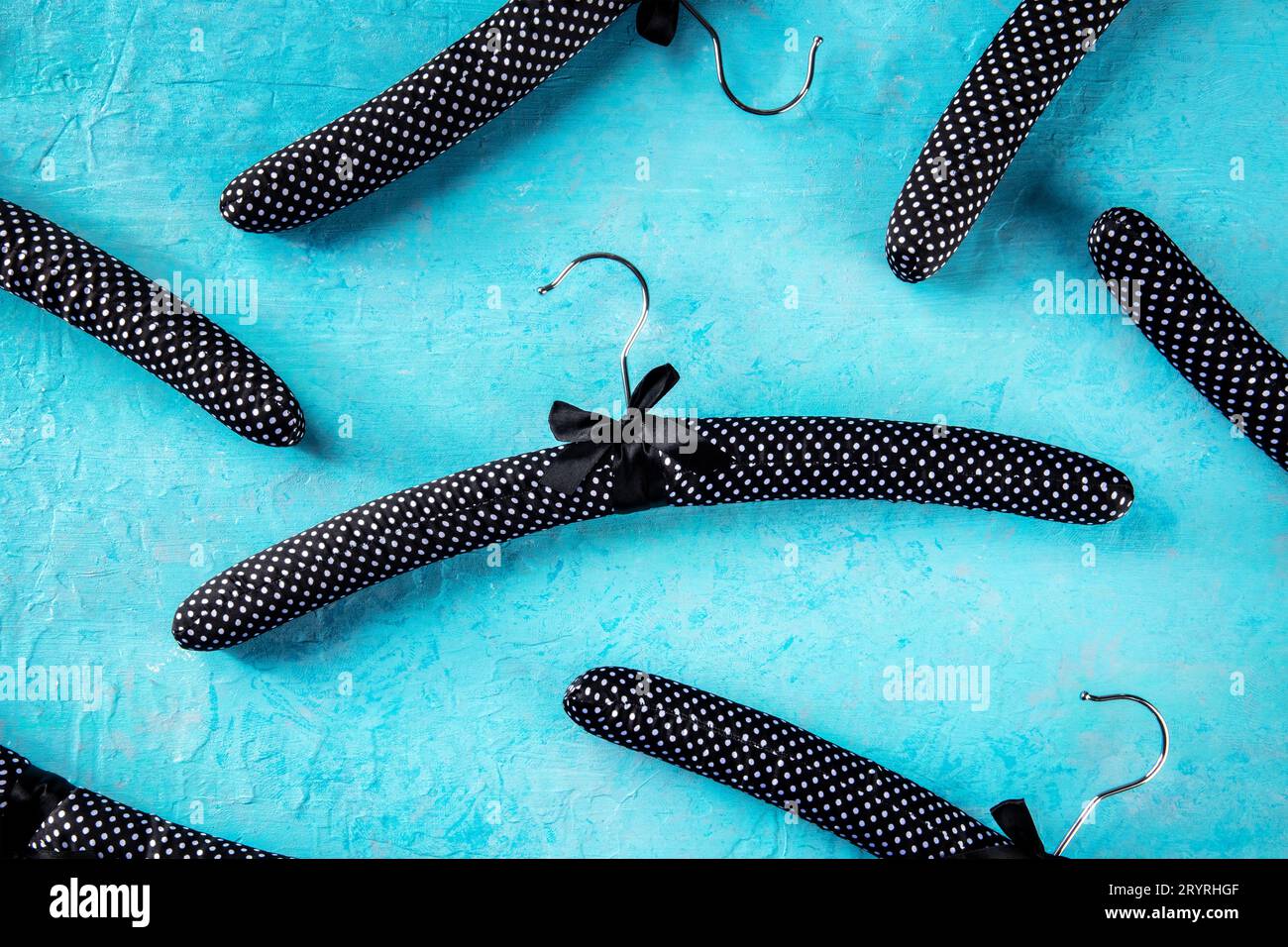 Fashion collection concept. Black satin hangers for delicate clothes, a flat lay layout on blue