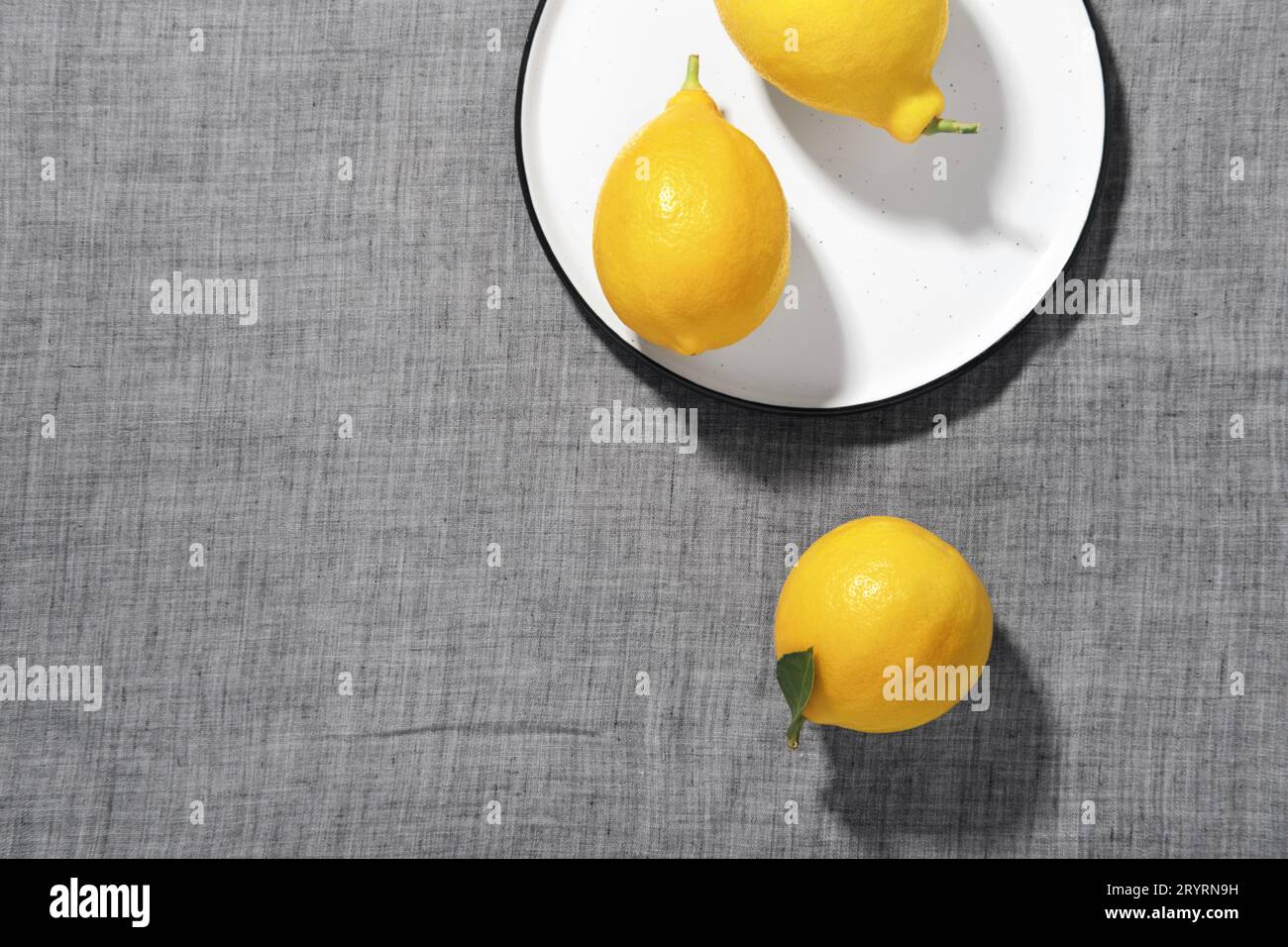 Trending colors of 2021. Yellow illuminating lemons and shadows on Ultimate gray tablecloth